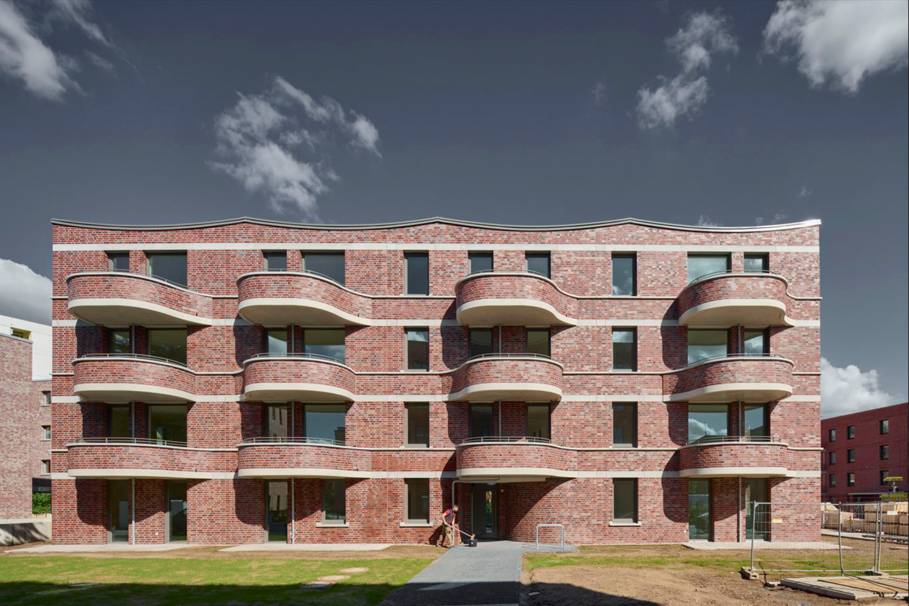 Die drei Mehrfamilienhäuser in Hannover hüllen sich in Klinkerkleid mit horizontalen Sichtbetonbändern und geschwungenen Details. © Olaf Mahlstedt