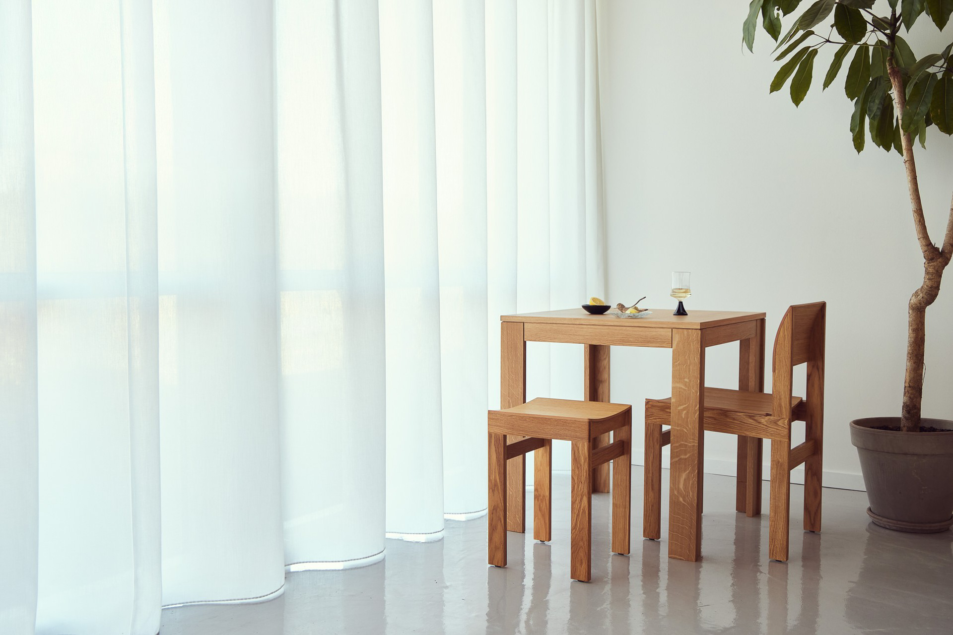 Tisch, Stuhl und Hocker aus Massivholz bilden eine kompakte Einheit mit klaren Querschnitten. Die sichtbaren Fügungen zeigen die einfache, statisch schlüssige Konstruktion. © Form & Refine