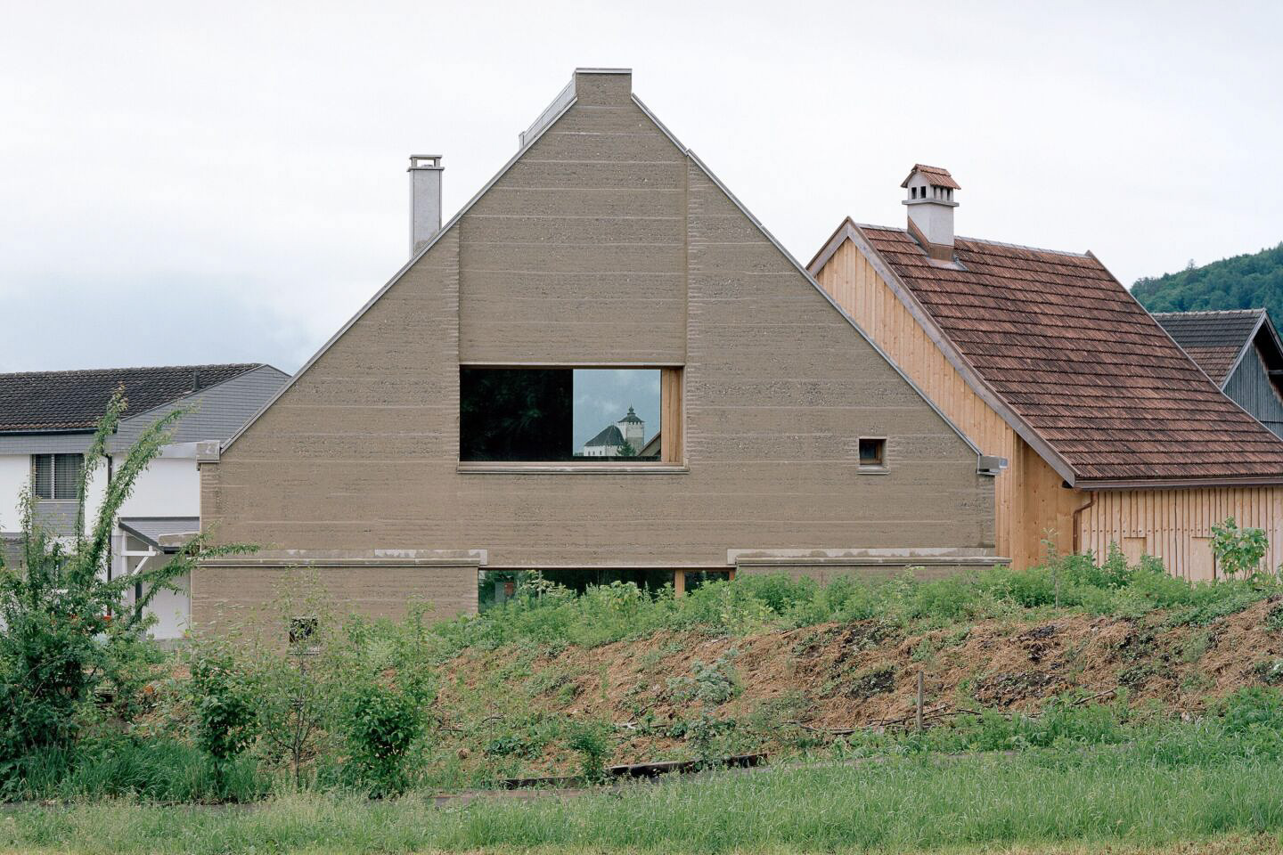 Der Neubau aus Stampflehm schließt über Eck an den historischen Strickbau an. © Rory Gardiner