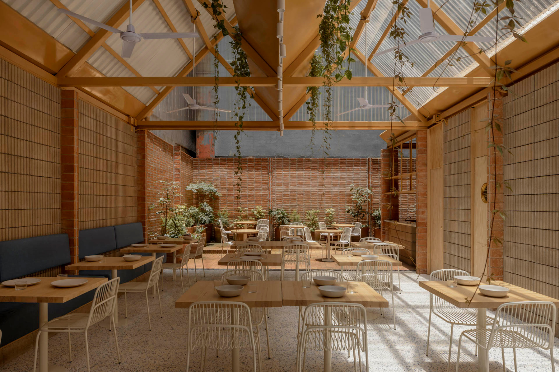 The interior of the Plumbago restaurant features natural materials, an abundance of daylight and an array of green plants. © Ariadna Polo