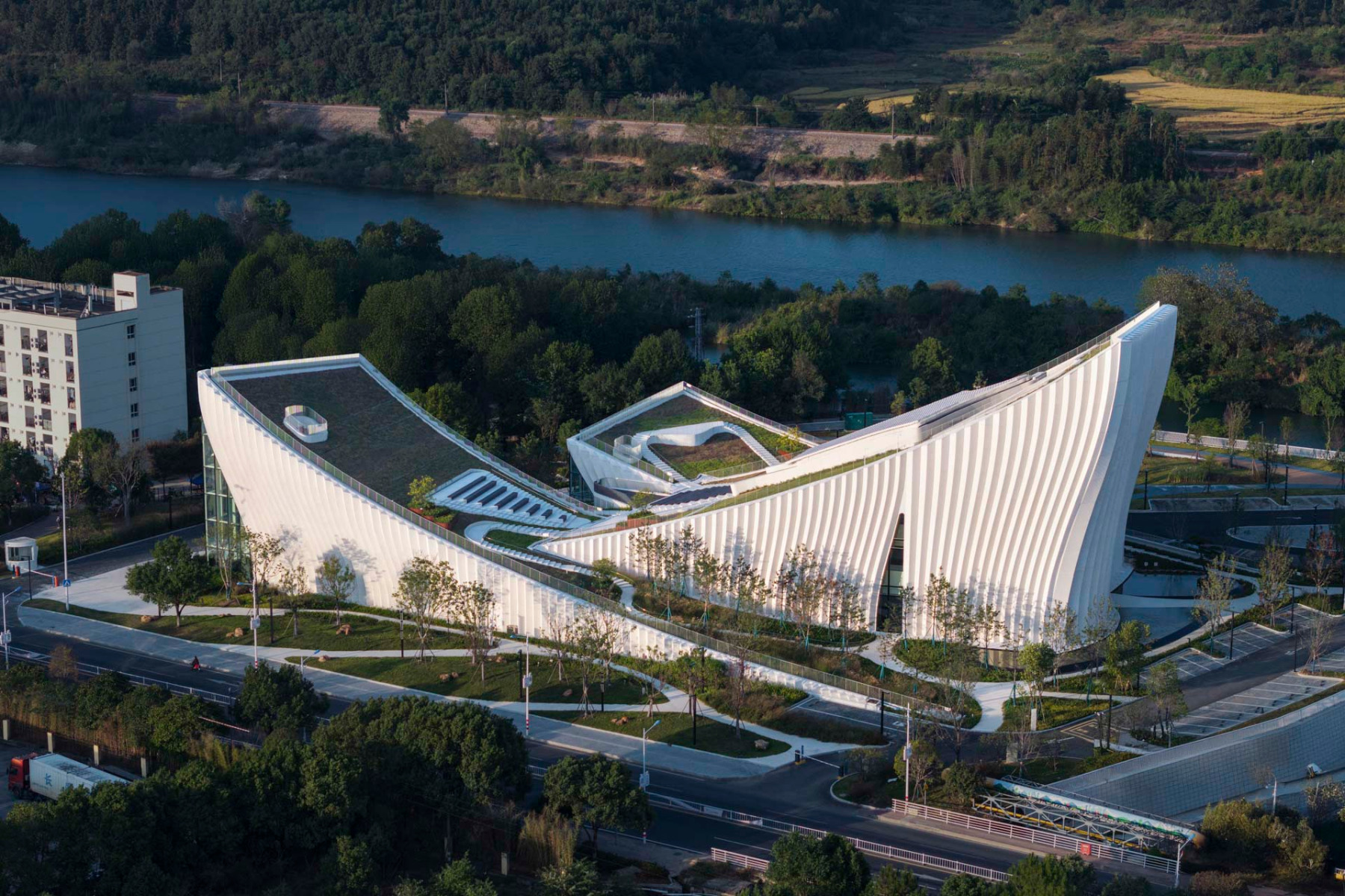 Drei&#x20;wechselseitig&#x20;geneigte&#x20;Bauk&#xF6;rper&#x20;mit&#x20;Gr&#xFC;nd&#xE4;chern&#x20;beherbergen&#x20;das&#x20;neue&#x20;Firmenmuseum.&#x20;Die&#x20;weitgehend&#x20;geschlossene&#x20;Geb&#xE4;udeh&#xFC;lle&#x20;ist&#x20;mit&#x20;gefalteten&#x20;Betonelementen&#x20;verkleidet.&#x20;&#xA9;&#x20;Cyan&#x20;&amp;&#x20;Orange&#x20;Images