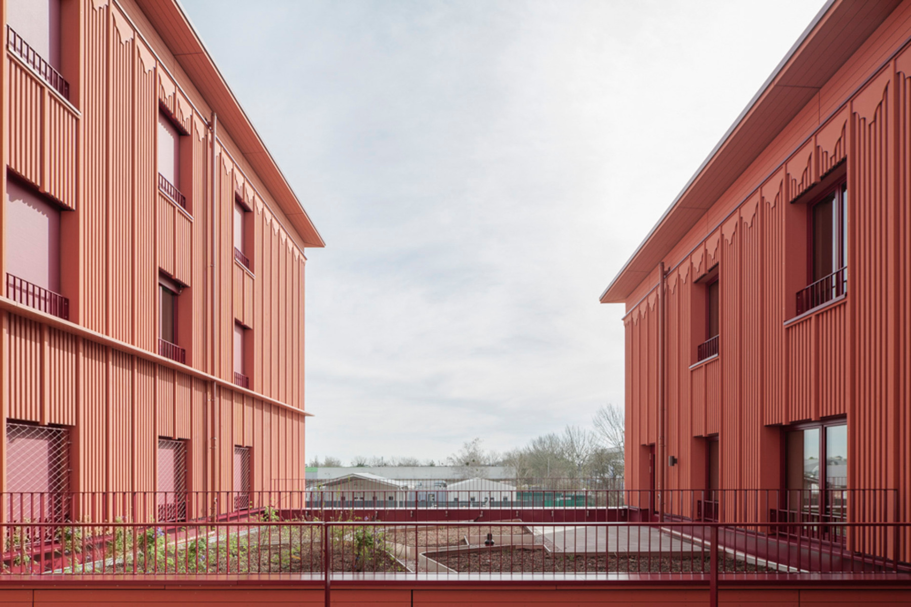 Die seriell vorgefertigten Holzrahmenelemente der Fassade sind ziegelrot gestrichen. © Florian Holzherr