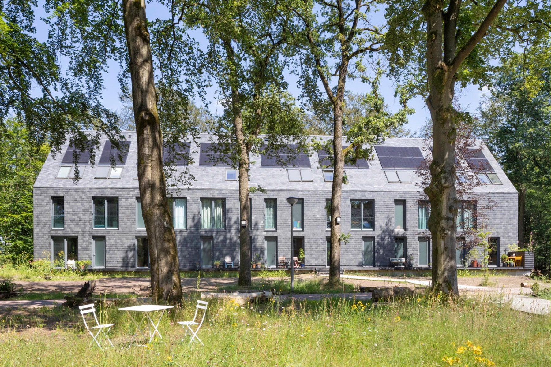 Lage, Kontur und Volumen der Reihenhäuser von MVRDV sind identisch mit verlorengegangenen Kasernengebäuden, die hellgrauen Schieferoberflächen machen sie als Rekonstruktionen erkennbar. © Daria Scagliola