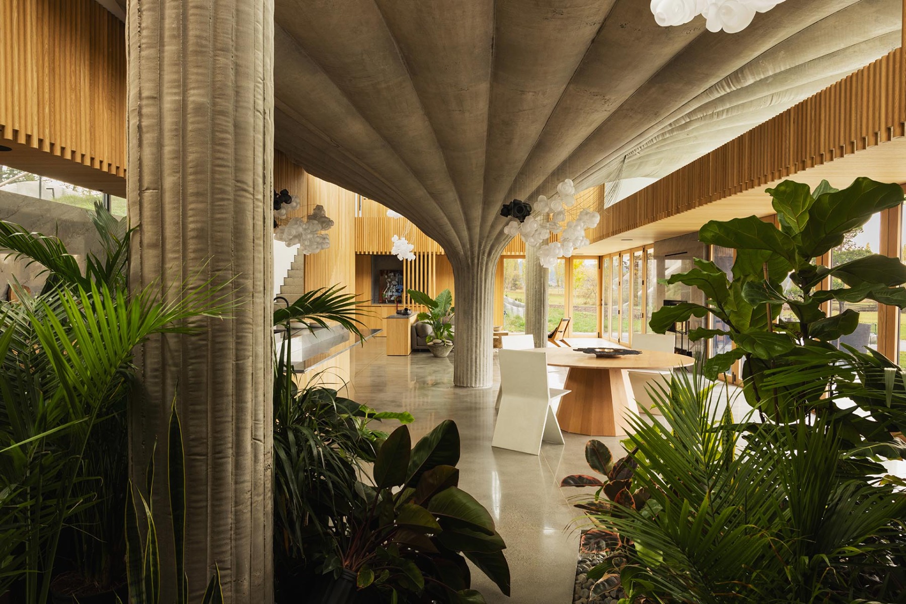 Das Wohnzimmer, der Essbereich und die offene Küche des Hauses 75.9 sind unter dem Vordach einer Seerosenblatt-Säule angeordnet. © Omer Arbel Office