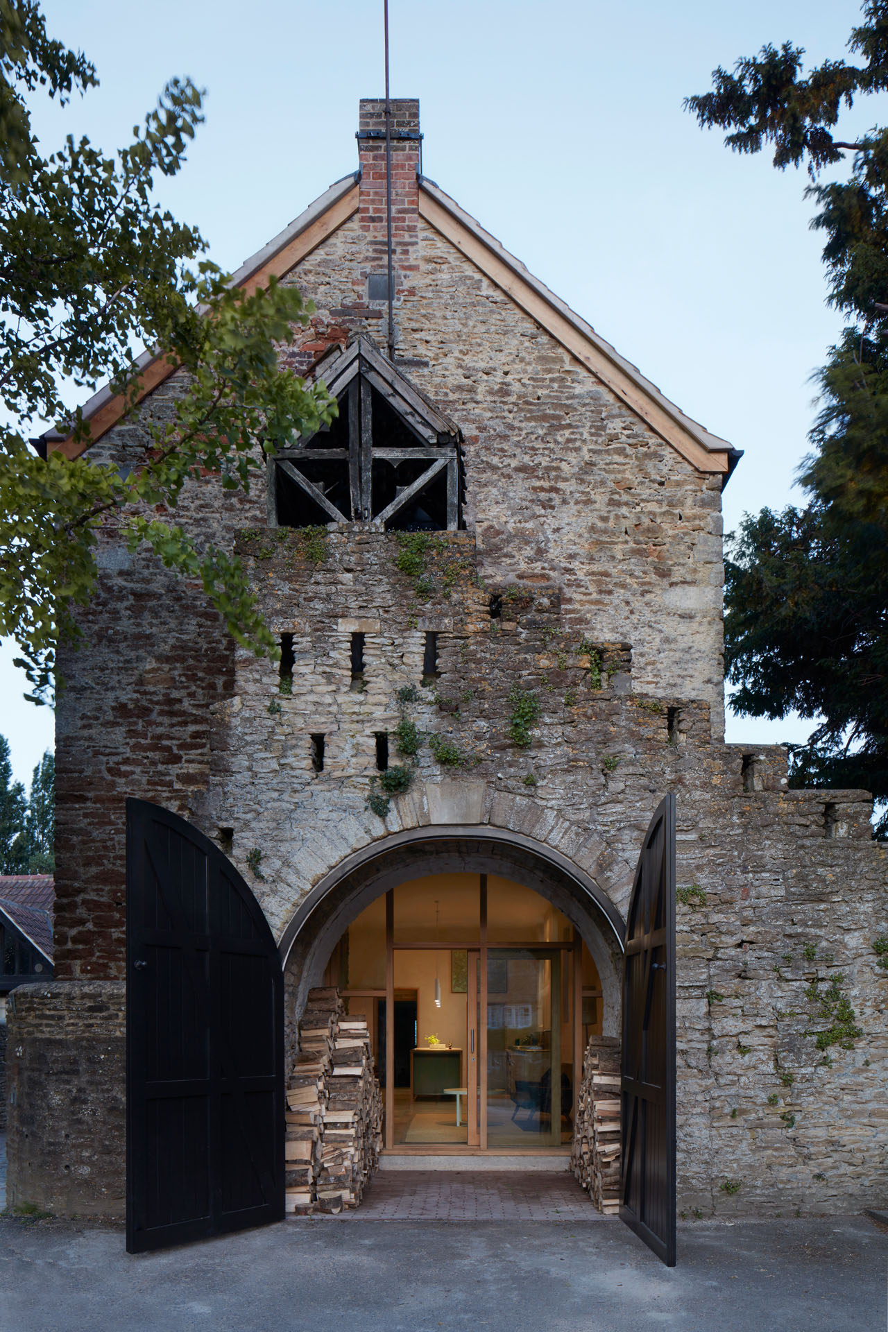 Exterior view with mottled brick facade, arched door open, view into the interior.