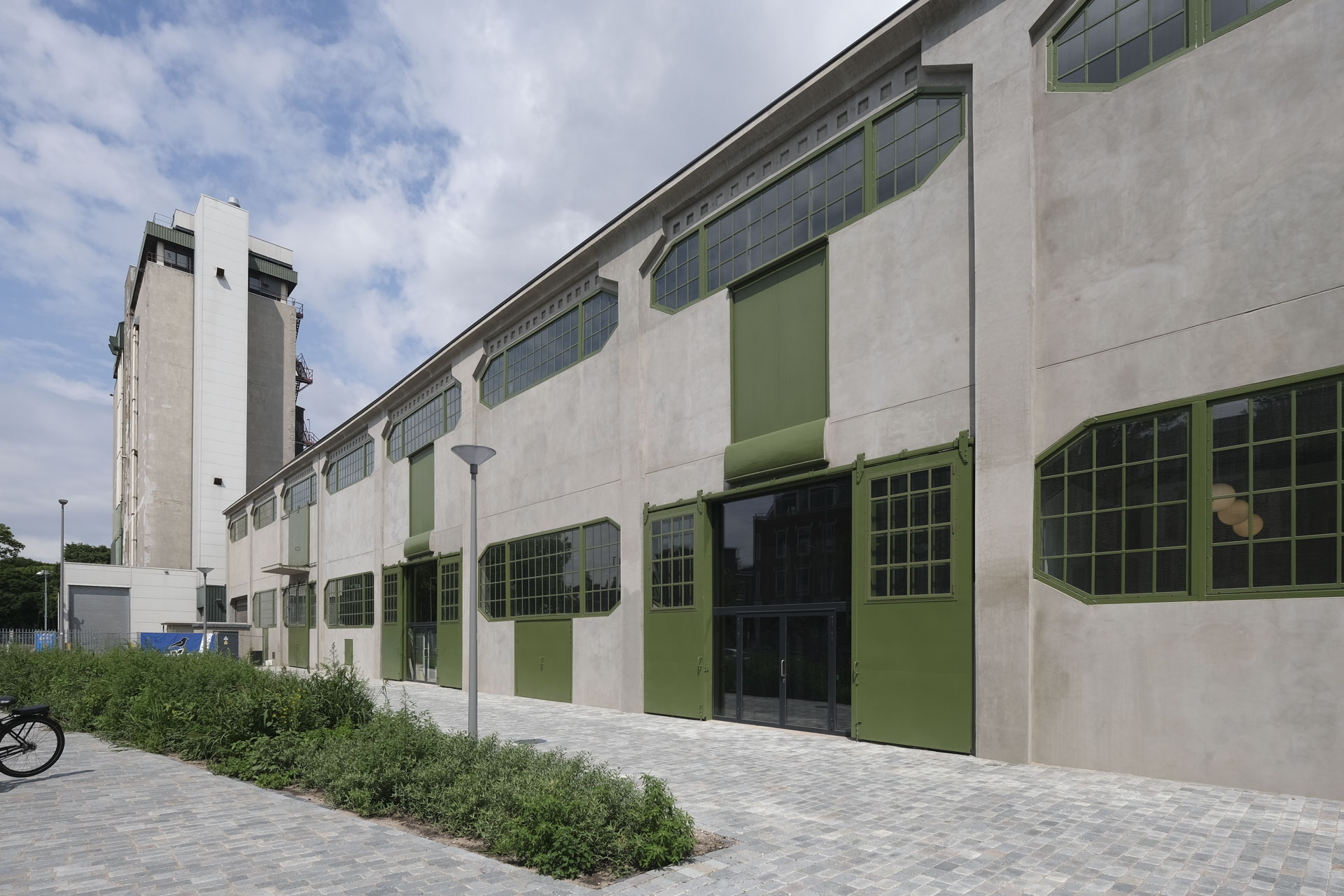 Former factory building, renovated, concrete facade, green window and door frames, exterior view.