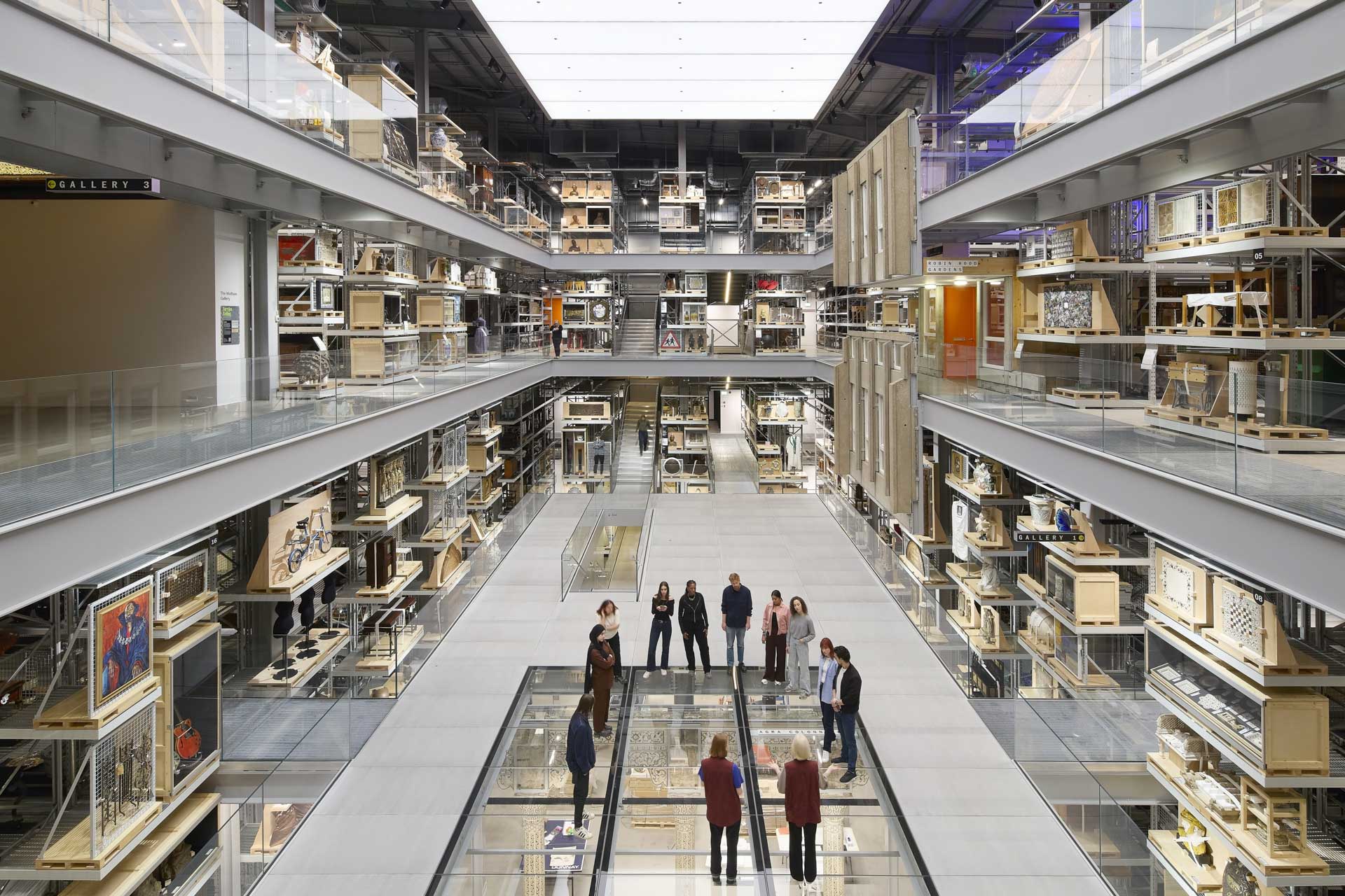 Group on glass floor in multi-story archive with glass and metal elements.