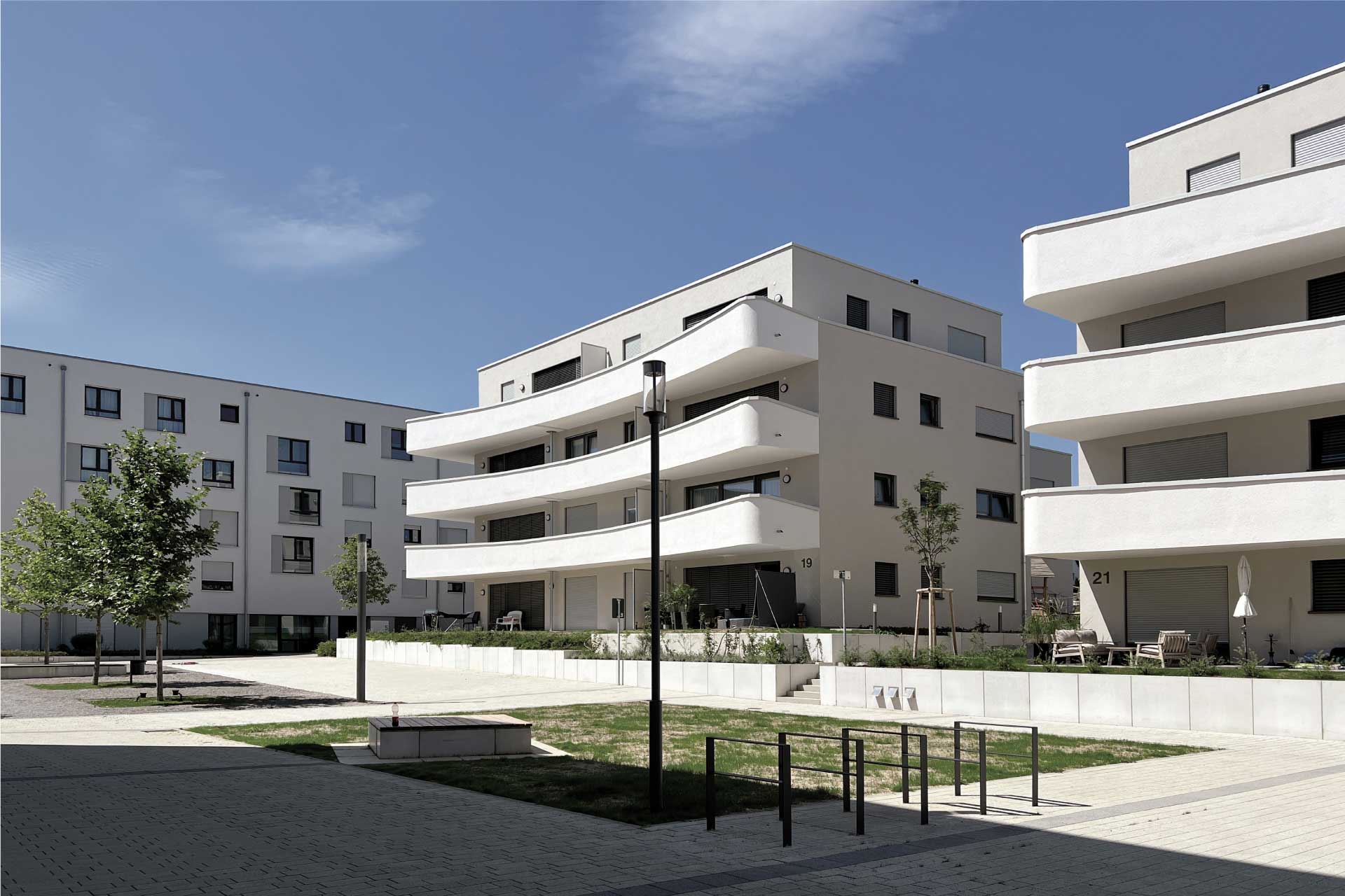 Wohngebäude mit weißer Fassade und durchgängigen Balkonen aus der Südseite.