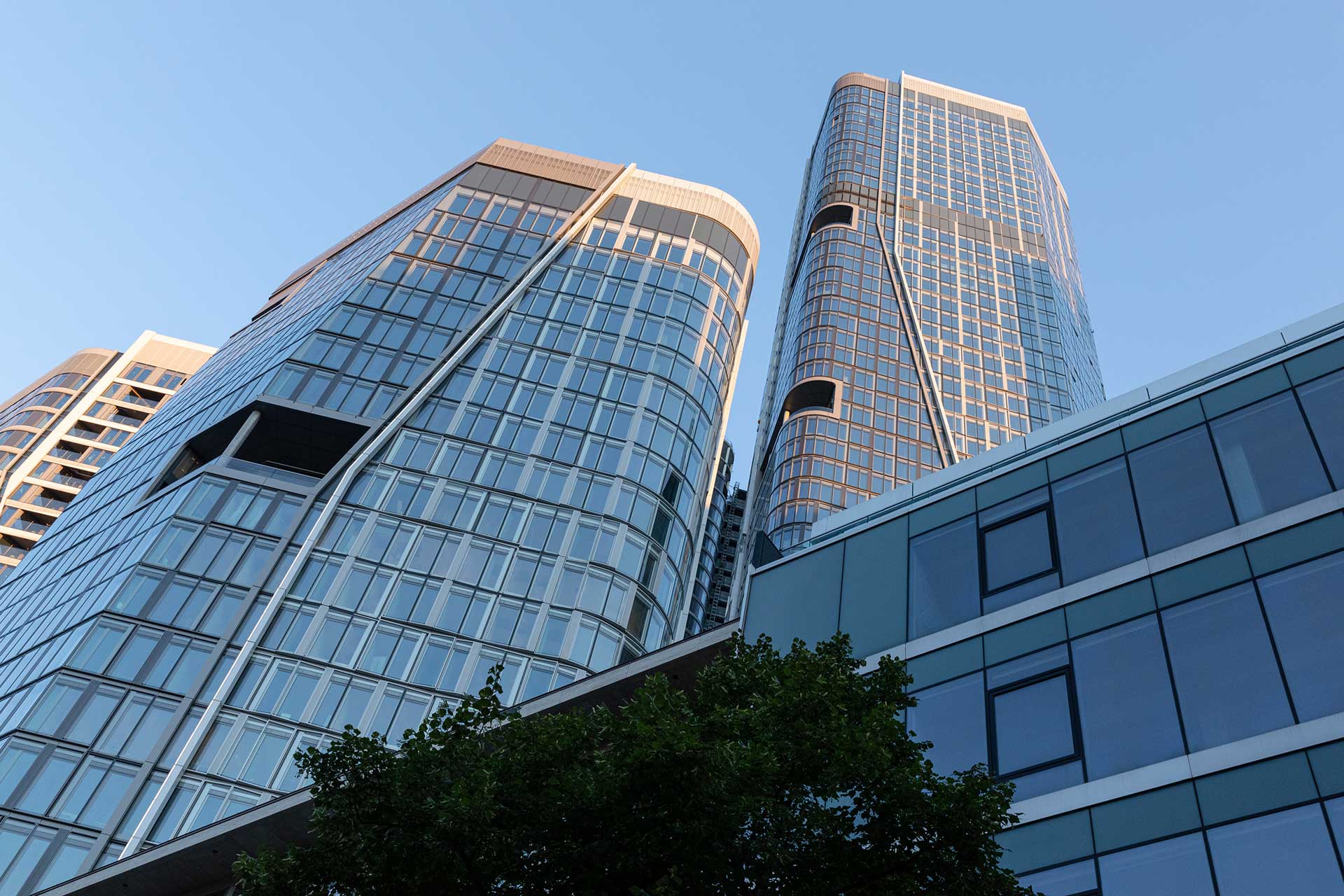 Zwei T&uuml;rme eines Hochhauses, die in den blauen Himmel ragen.