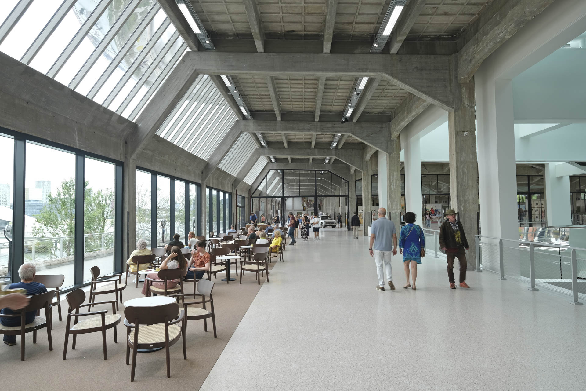 Open interior, visible concrete construction, high ceilings, large windows, bright, flowing room layout.