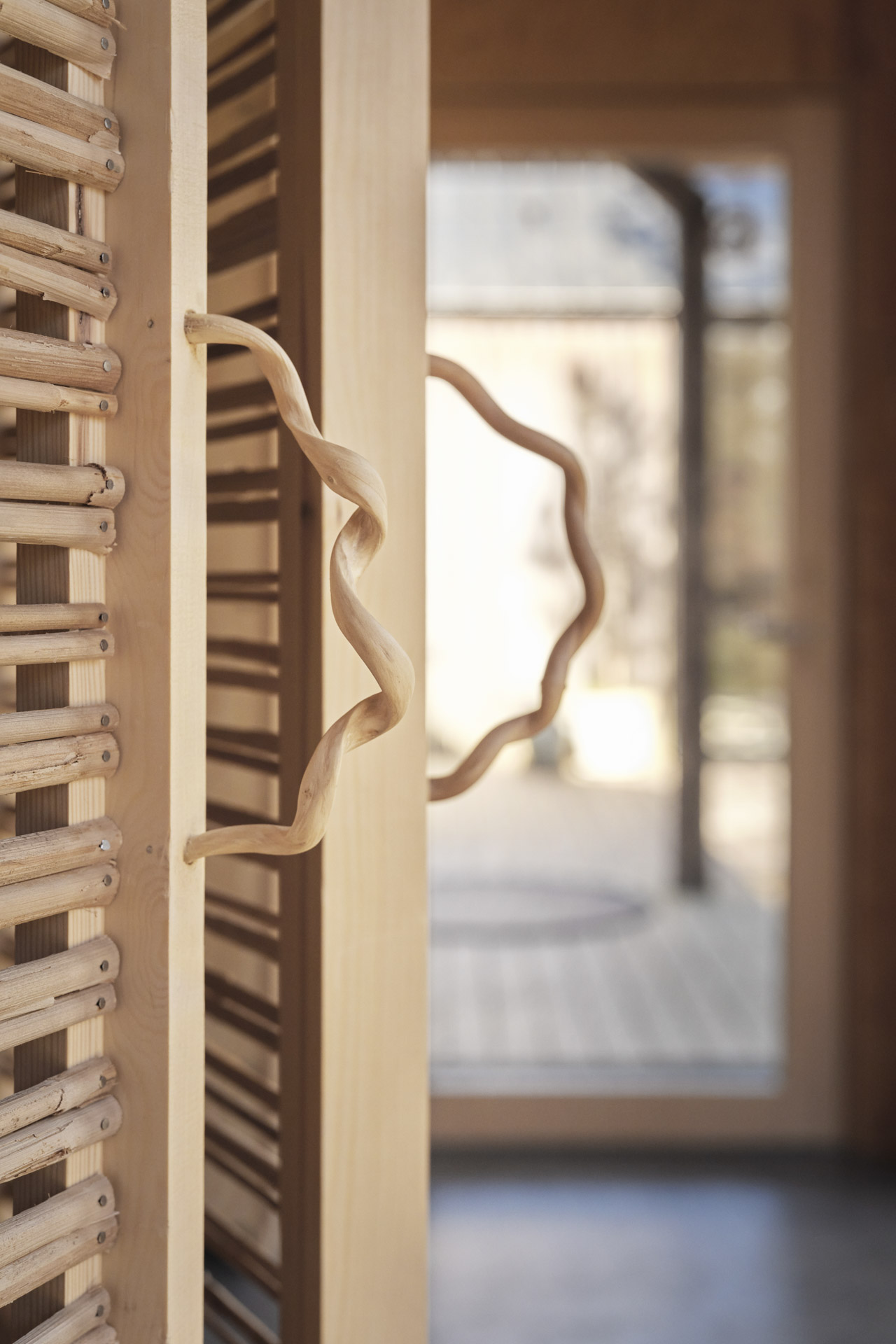Close-up of a wooden slatted door with turned wooden door handle in the interior.