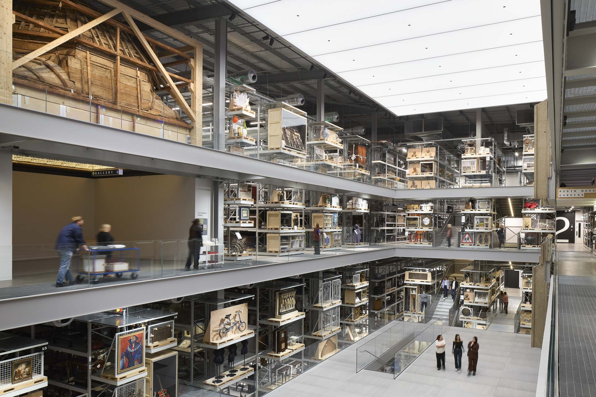 Multi-story archive with atrium opening, skylight illuminates the filled rows of shelves with various objects.