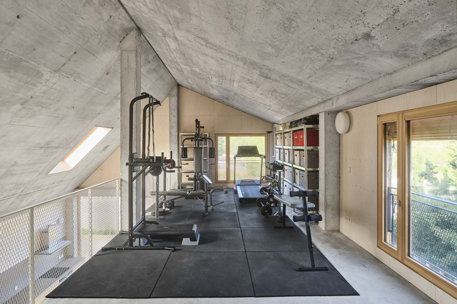 Halbgeschoss unter betoniertem Dachgiebel, eingerichtet als Home-Gym.