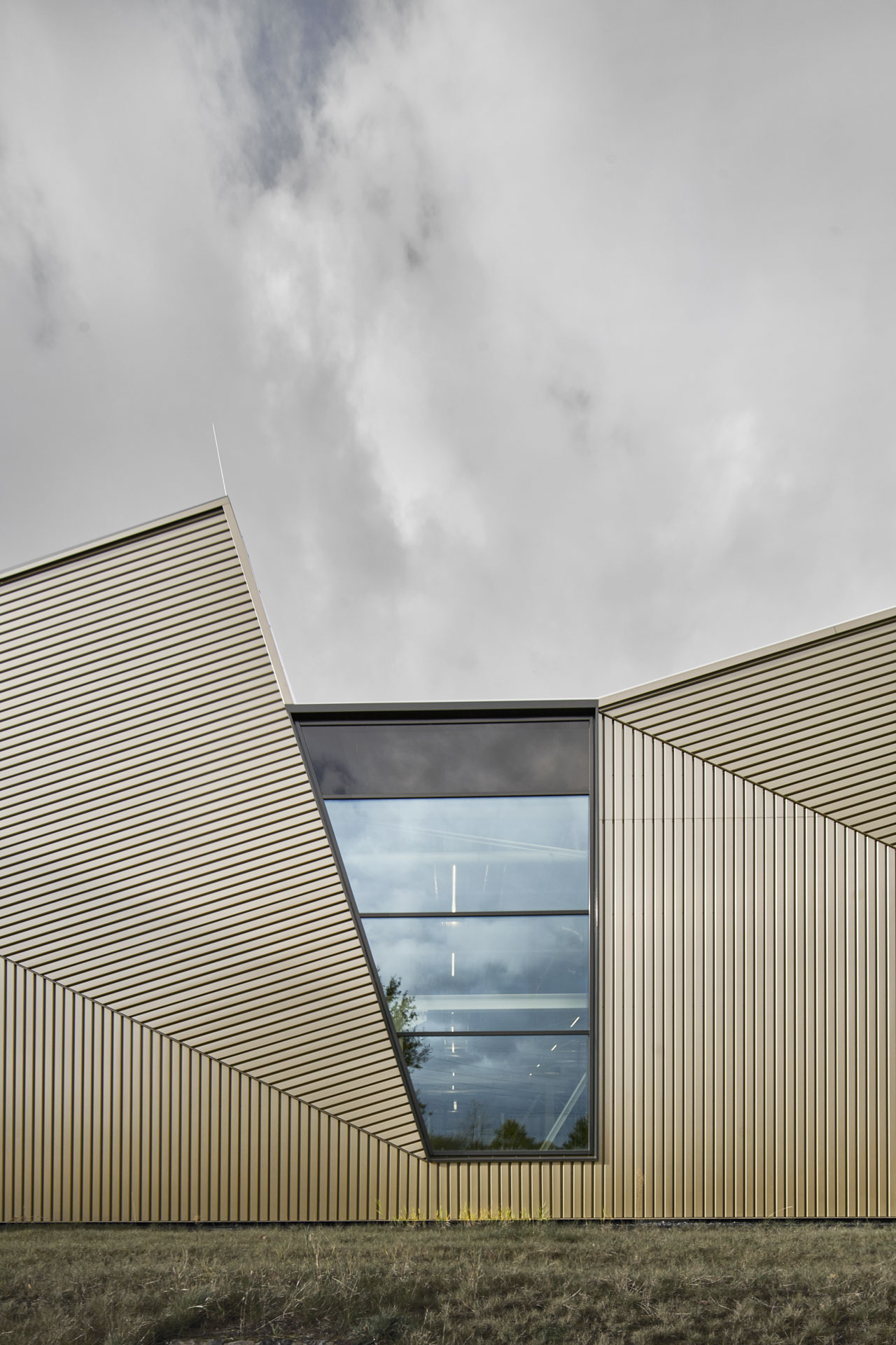 Gebäudefassade mit Sheddach, Metallverkleidung und großformatiger Fensteröffnung.