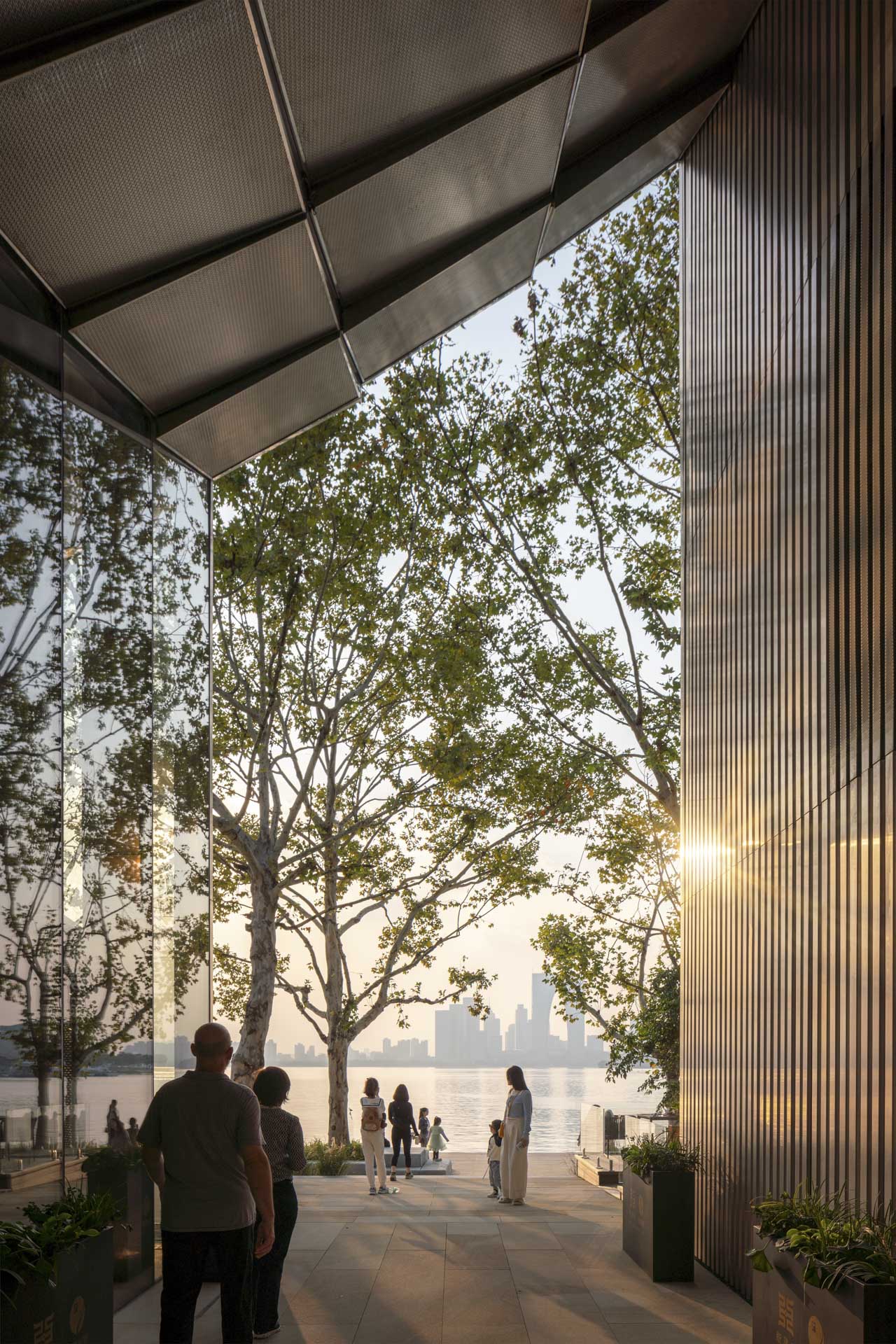 Covered passage with a textured ceiling and metal façade. The view is directed toward the evening dusk and the skyline.