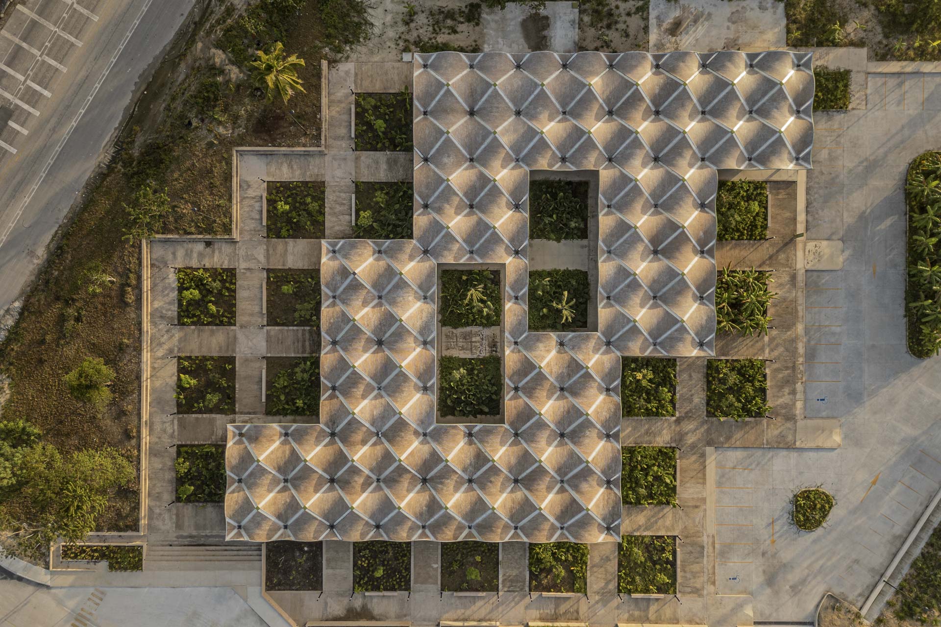 Dachaufsicht eines Gebäudes aus Stahlbeton mit rasterförmiger Struktur; abwechselnd Wege, begrünte Höfe und geschwungene Dachflächen.