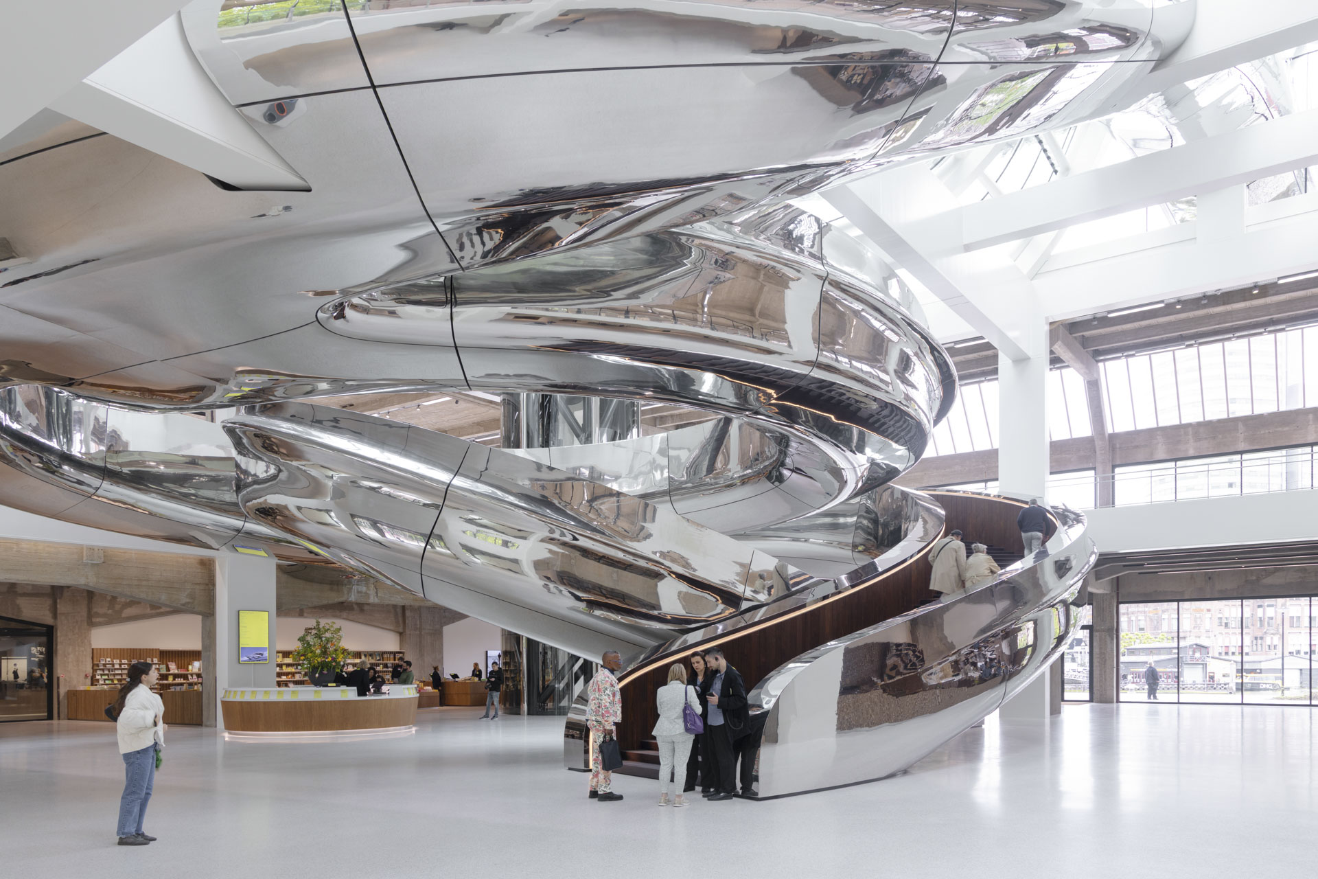 Massive metal ramp in the form of a spiral winds its way up to the upper floor in the bright atrium.