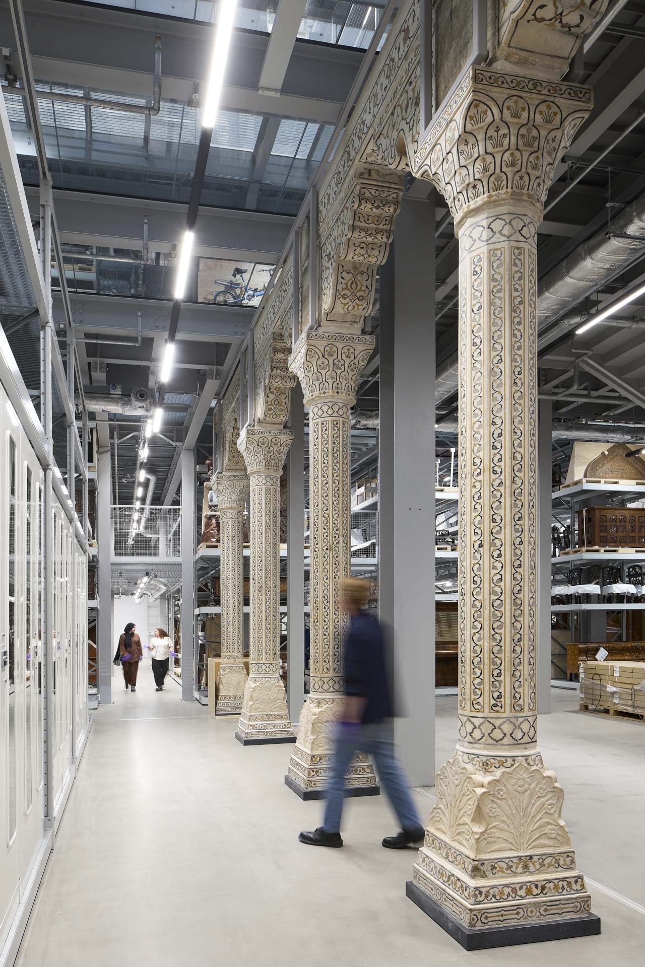 Ornate row of columns amid metal shelving walls.