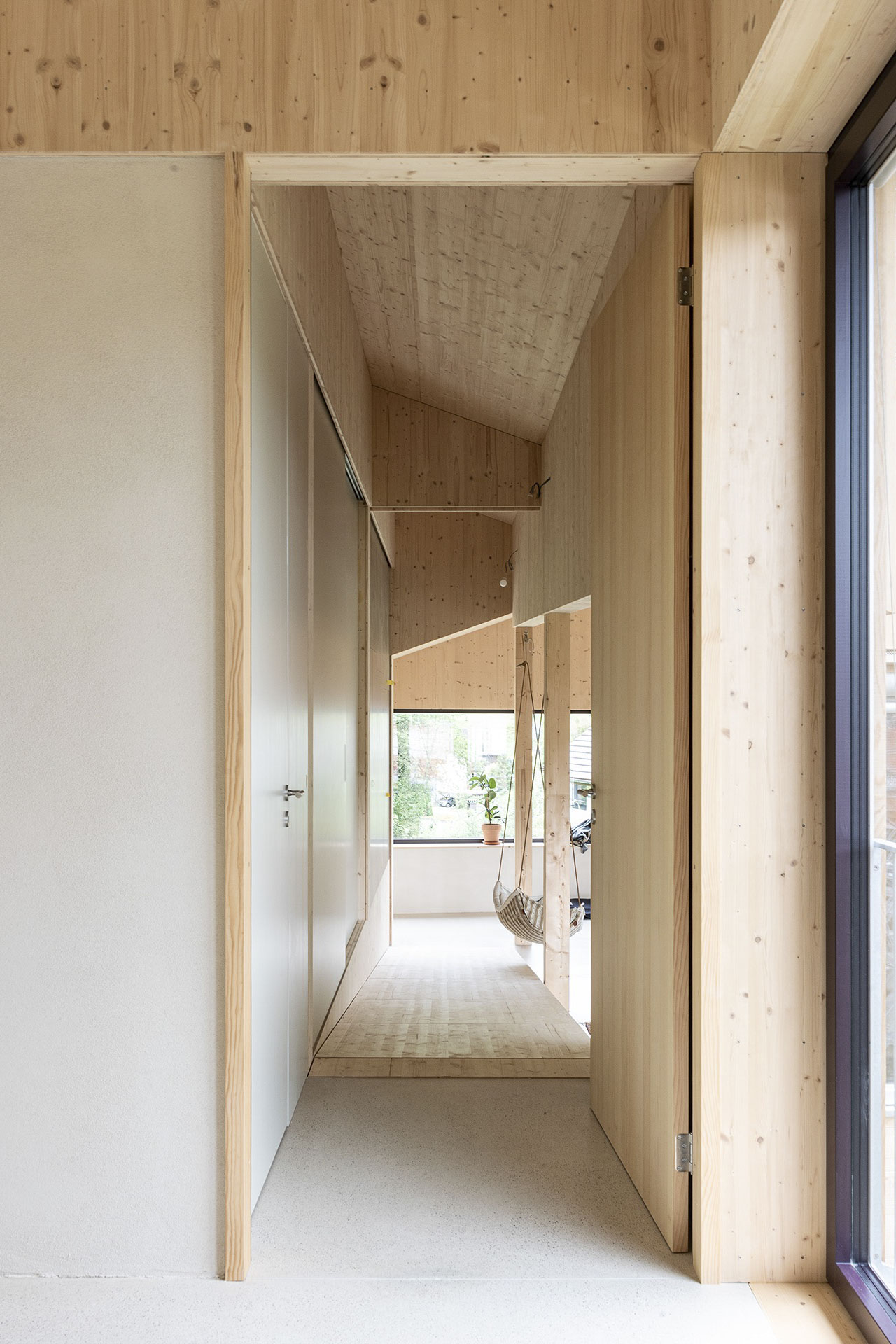 Wohnflur mit Holzoberflächen und seitlicher Verglasung, der den Blick in den angrenzenden Wohnraum öffnet.