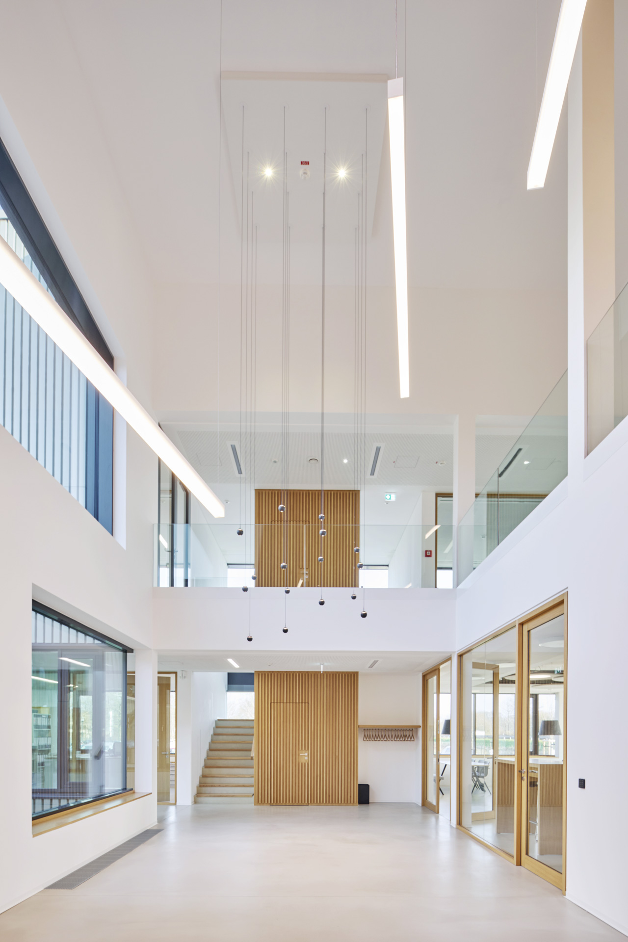 Zweigeschossiges Atrium mit Holz, Glas und Licht als zentrale Gestaltungselemente – klar, offen und funktional.