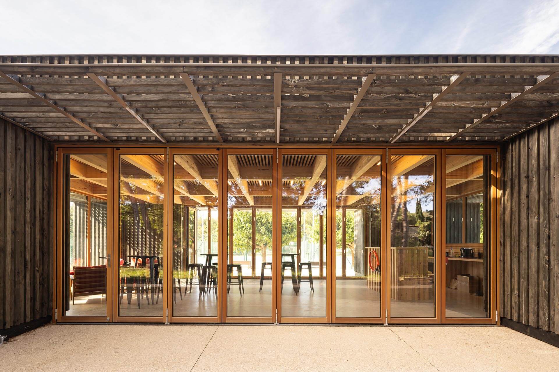 Blick in einen großen, offenen Raum durch eine faltbare Glaswand.