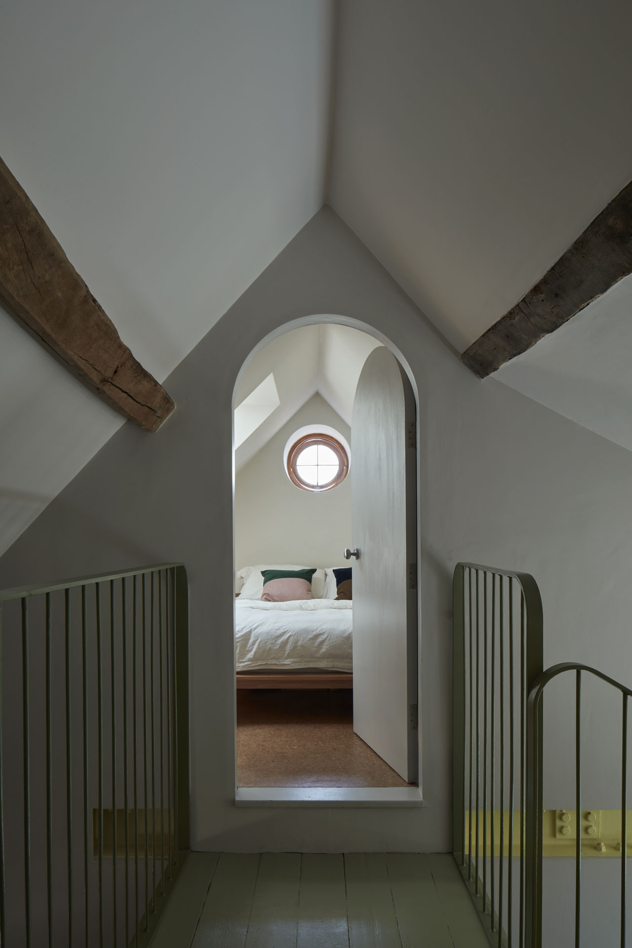 In the attic, a walkway leads to the bedroom. The arched door is open, offering a clear view into the bedroom.