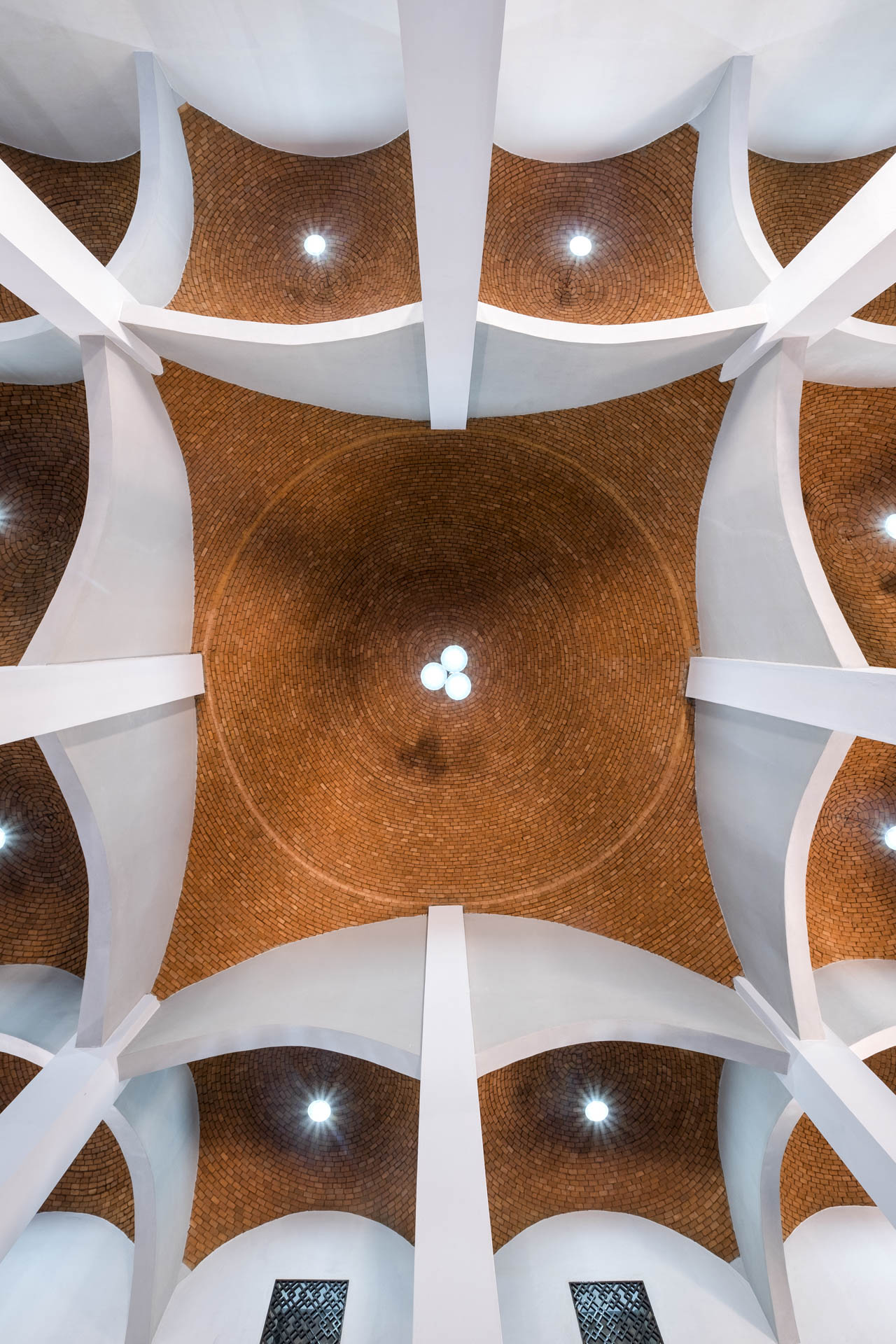 Blick von unten auf ein Ziegelgewölbe, modern interpretiert, mit geschwungenen Stahlbetonträgern auf Säulen gestützt.