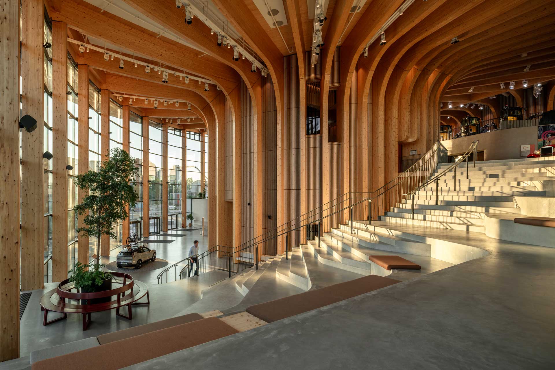 Großes Atrium mit verglasten Außenwänden, Steintreppen zum sitzen und mittig ein großer, runder Stützpfeiler.