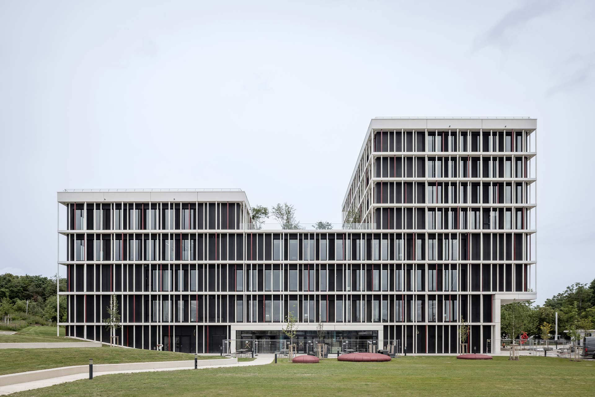 Freistehendes Gebäude mit unterschiedlichen Geschosshöhen und Stabfassade.