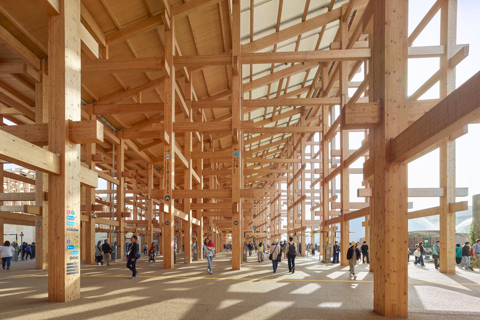 Modern exhibition space with numerous light objects, large screen wall and several visitors.