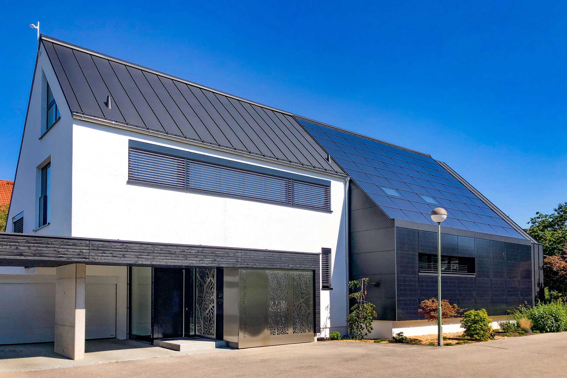 Einfamilienhaus mit überdachtem Eingangsbereich und Photovoltaik auf dem Dach.