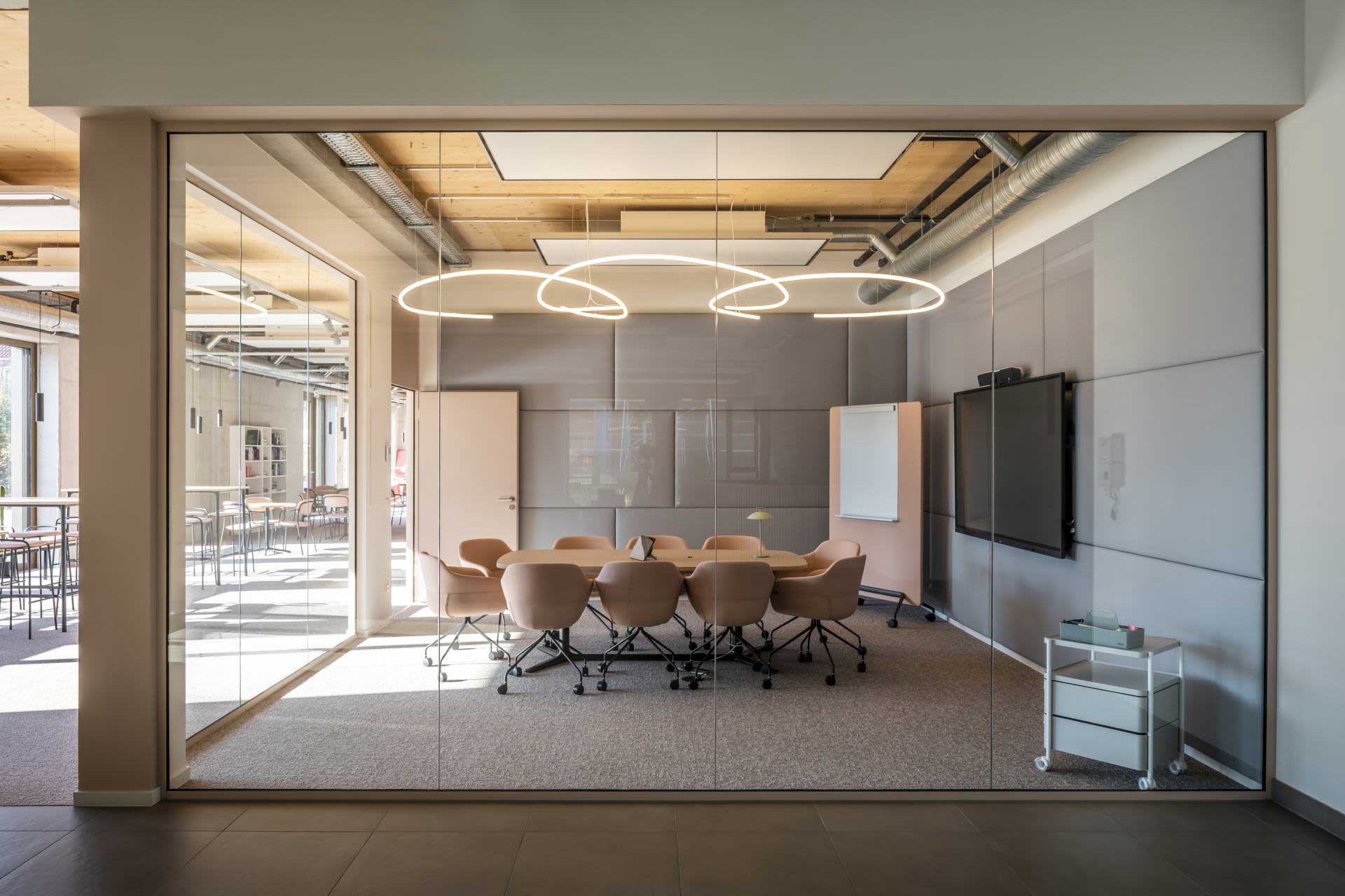 Verglaster Besprechungsraum in einem Büro mit Tisch und mehreren Stühlen darum.