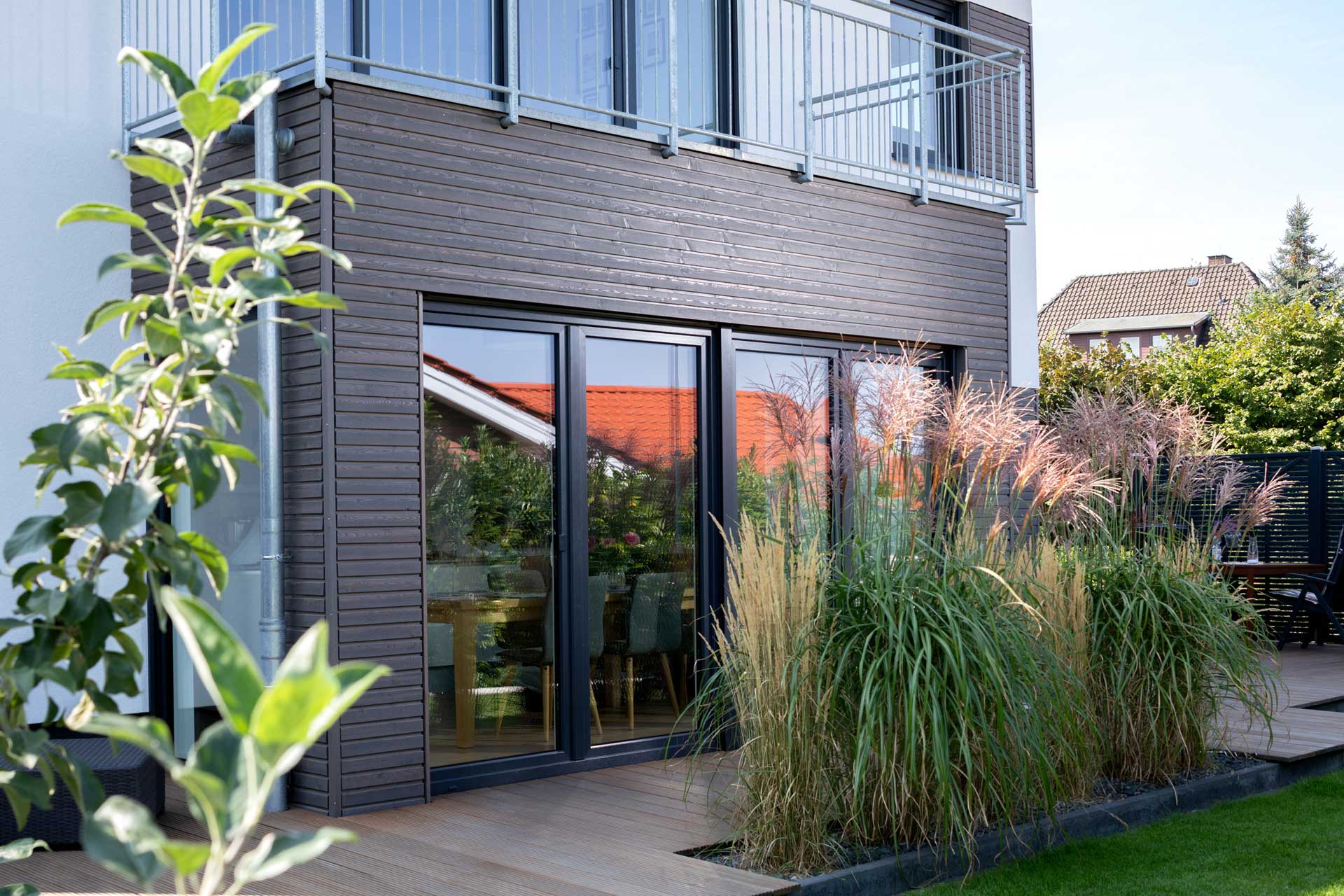 Haus mit Garten und einem holverkleidetem Erker.