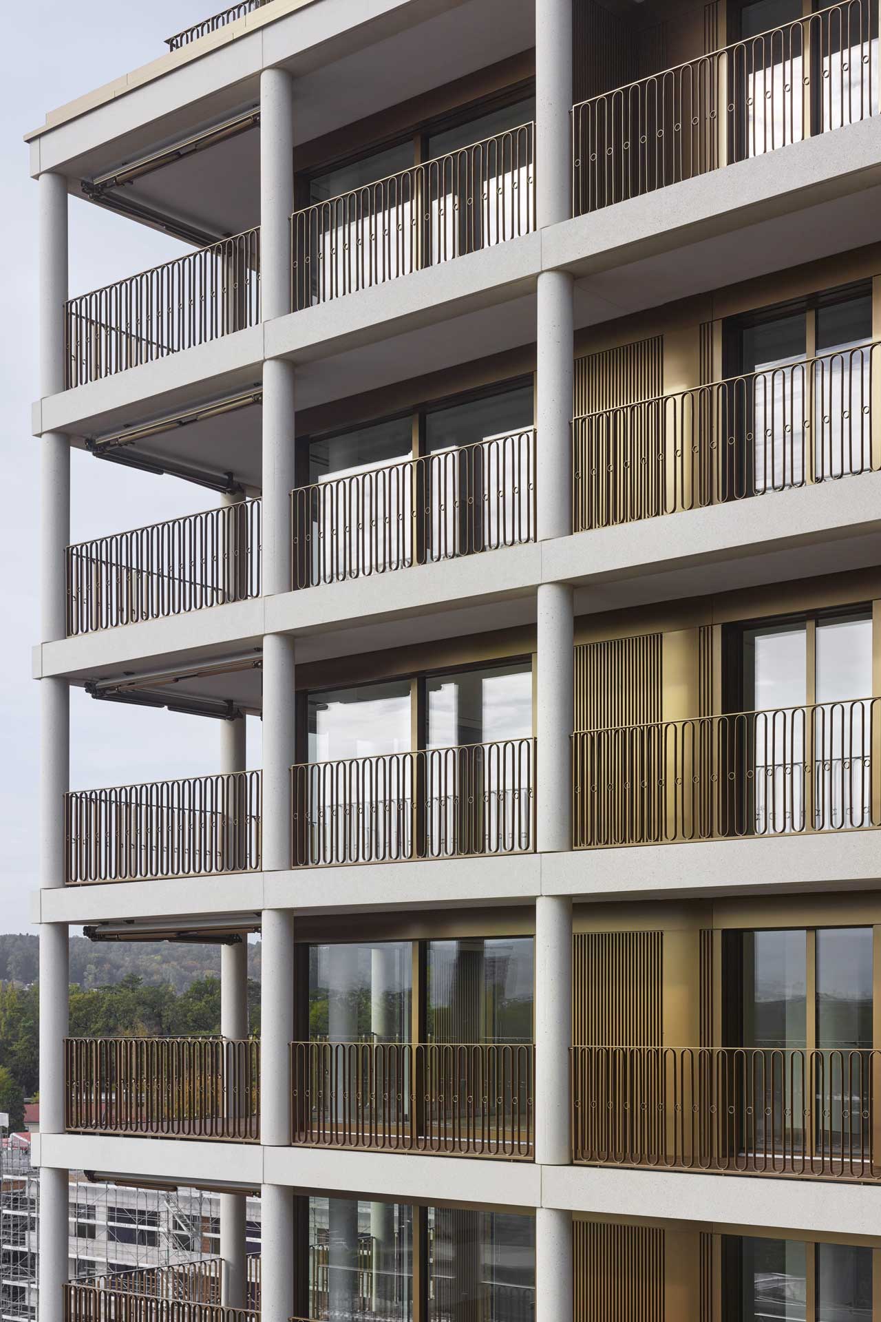 Wohnhaus mit durchgängig angeordneten Balkonen mit goldfarbenen Balkongittern.