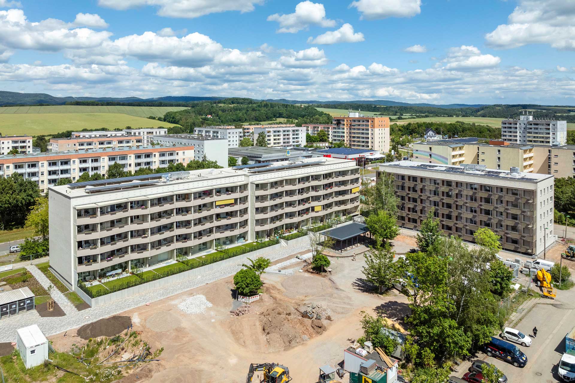 Sanierte Wohnbausiedlung mit mehreren Wohnhäusern mit Flachdächern. Die Grünanlagen sind noch im Bau.