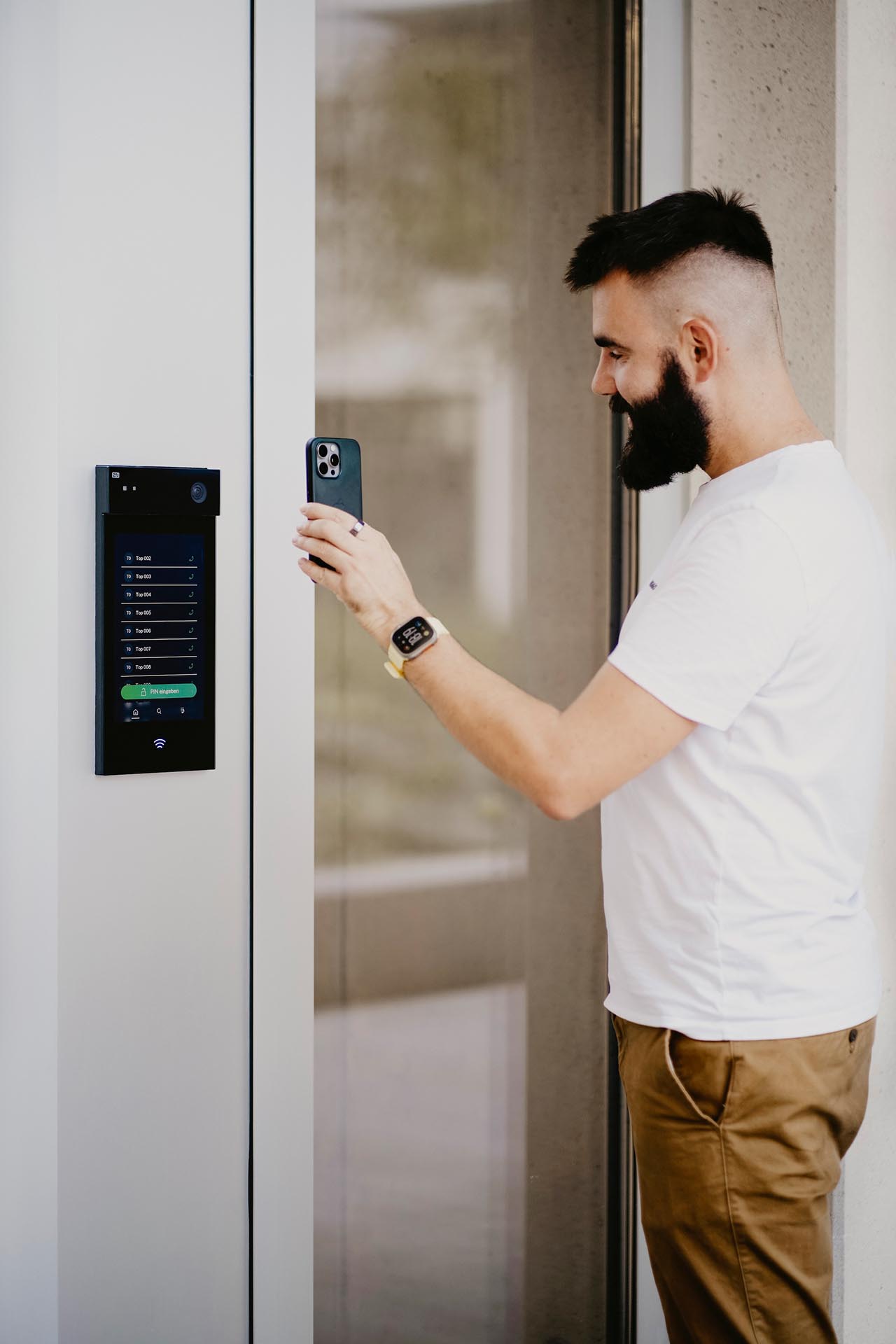 Ein Mann öffnet die Tür mit Hilfe seines Handys an der elektronischen Zutrittskontrolle.