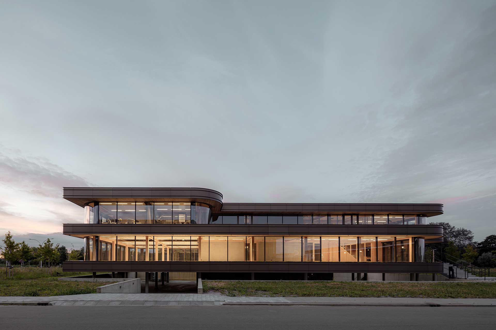 Beleuchtetes, zweistöckiges Bürogebäude in der Abenddämmerung.