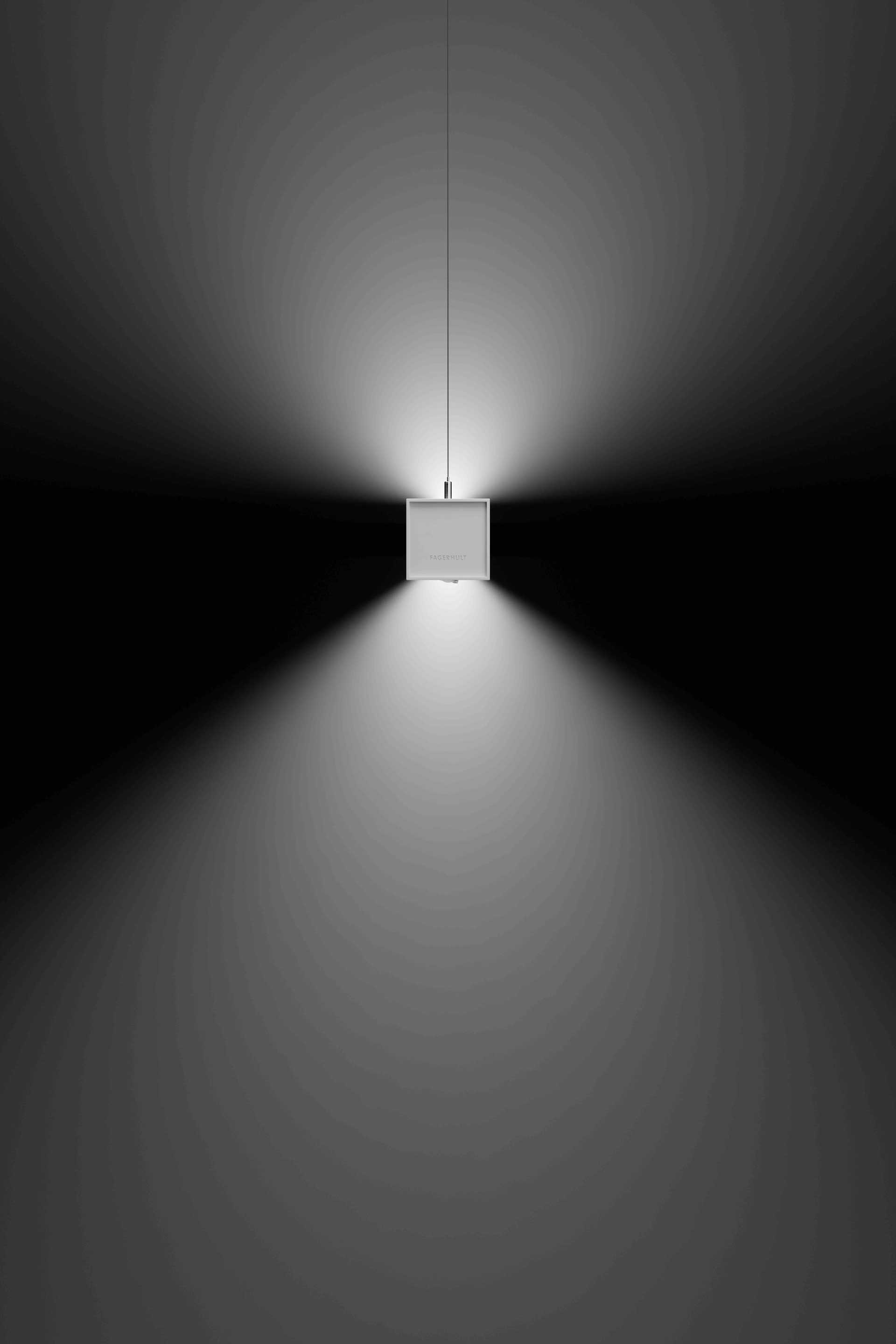 Eine weiße, quadratische Leuchte strahlt eine Wand an.