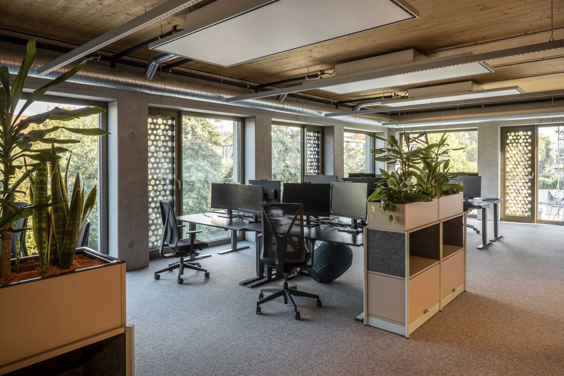 Büro mit voll ausgestatteten Arbeitsplätzen, die als zwei Viererinseln gruppiert sind.