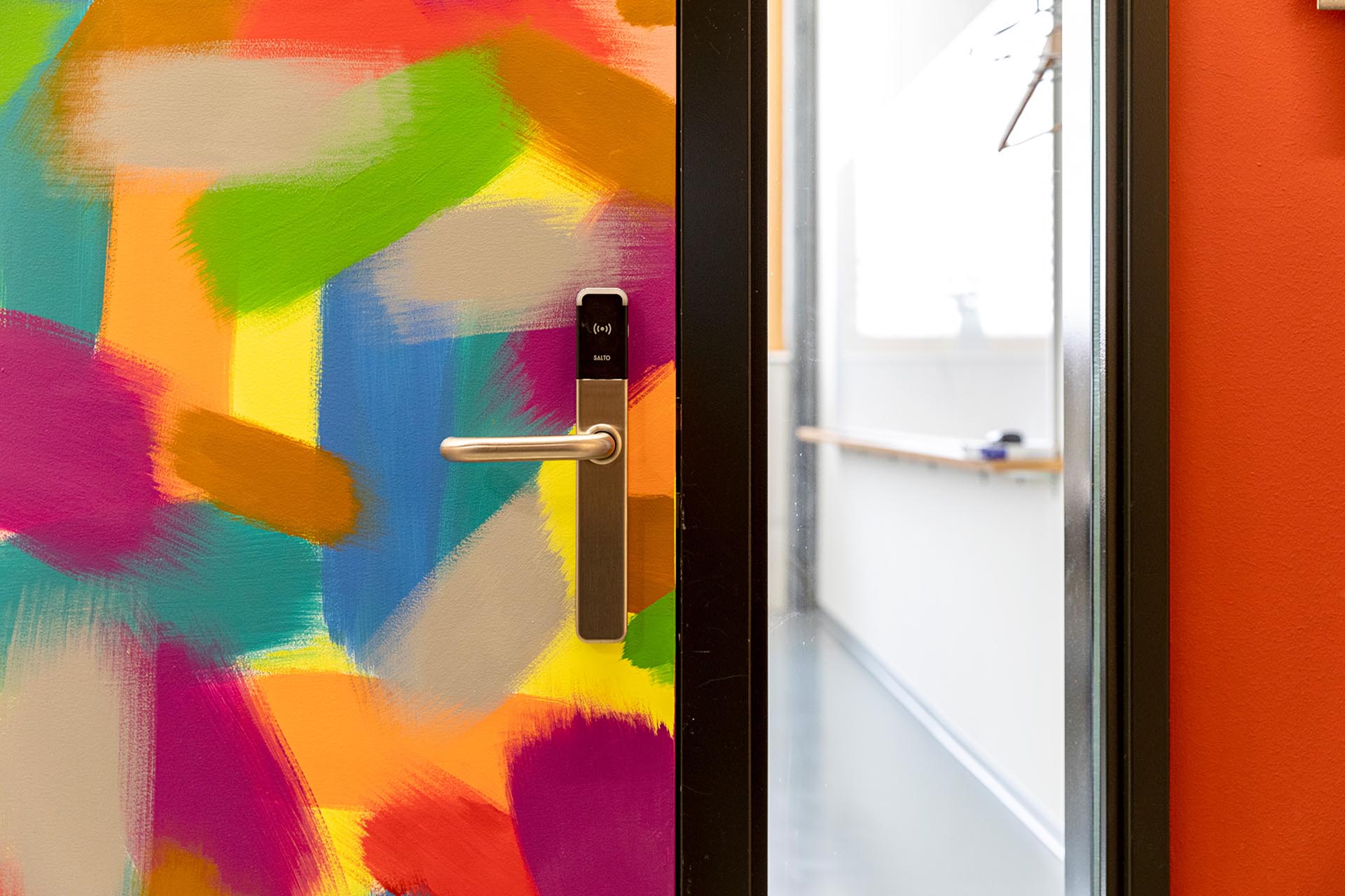 Bunt bemalte Tür mit Zutrittskontrolle an der Klinke.