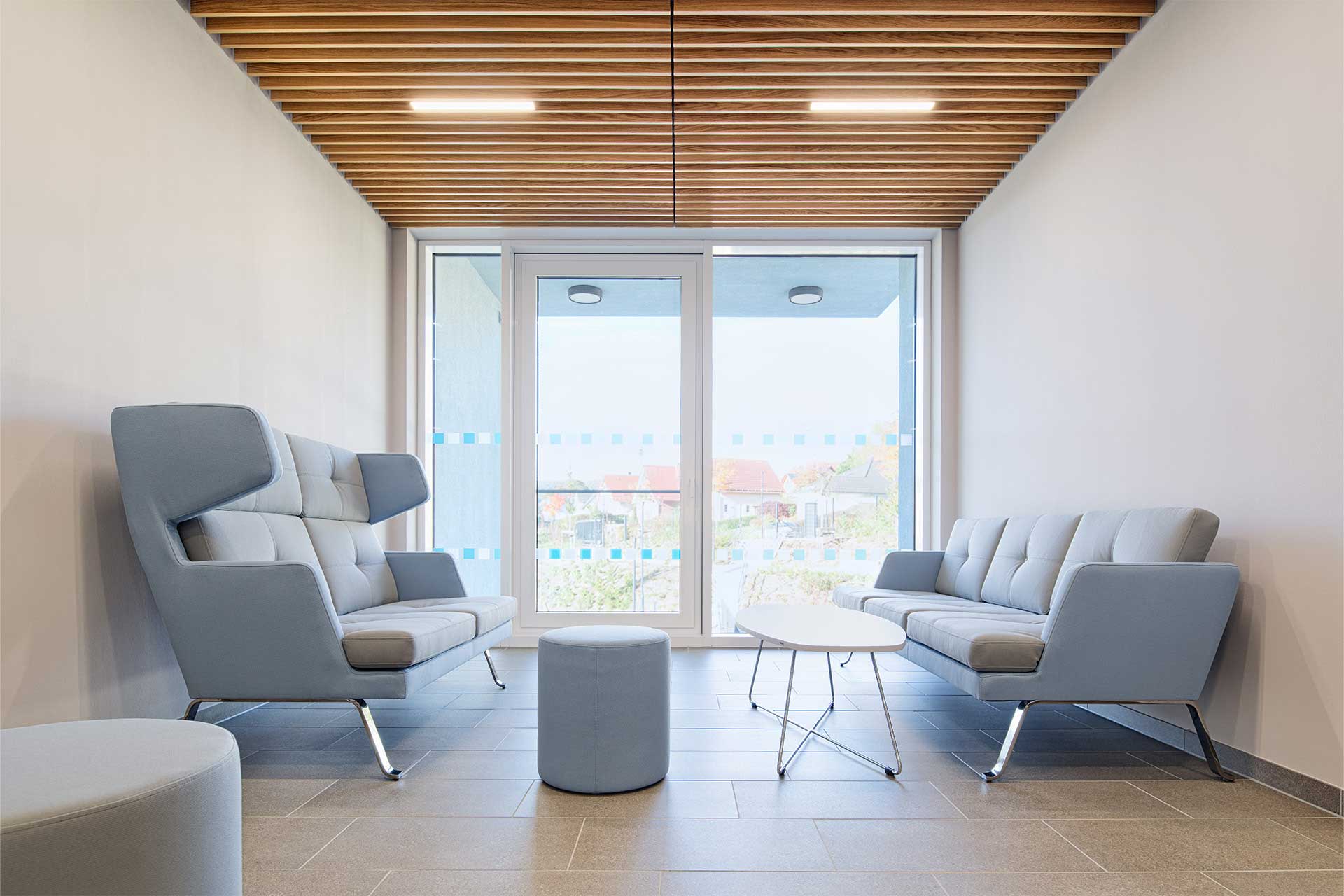 Lichtdurchfluteter Raum mit zwei sich gegenüberstehenden, blauen Sofas und einem tiefen Tisch in der Mitte.