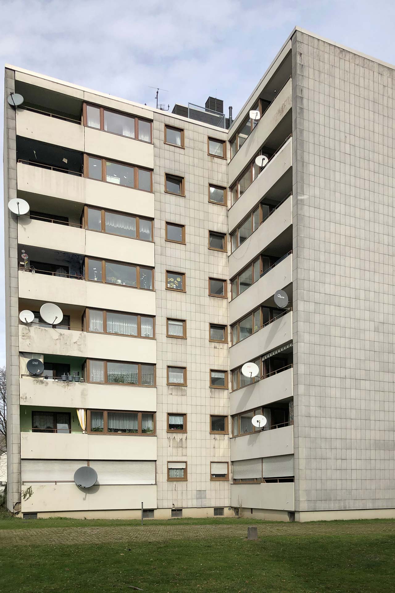 Mehrfamilienhaus aus den 70ern mit heruntergekommener Fassade.