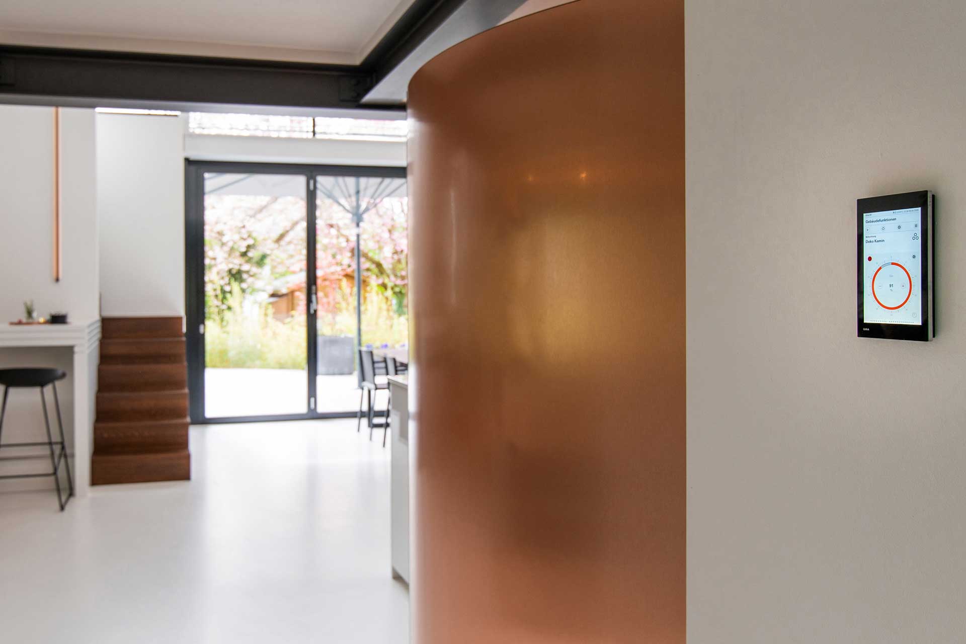 Durchgang zu einem Wohnzimmer mit einer Smart Home Konsole an der Wand.