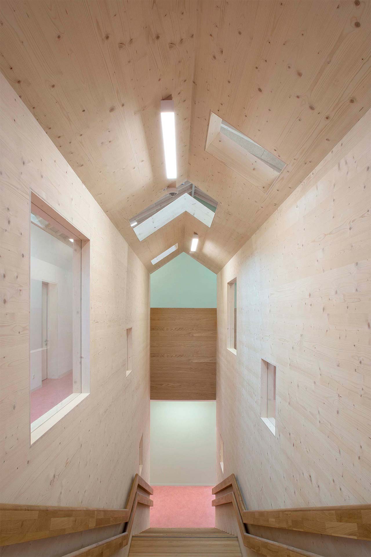 Holztreppe in einer Kita, die links und rechts mit Holzw&auml;nden und einer hohen Holzdecke begrenzt ist.