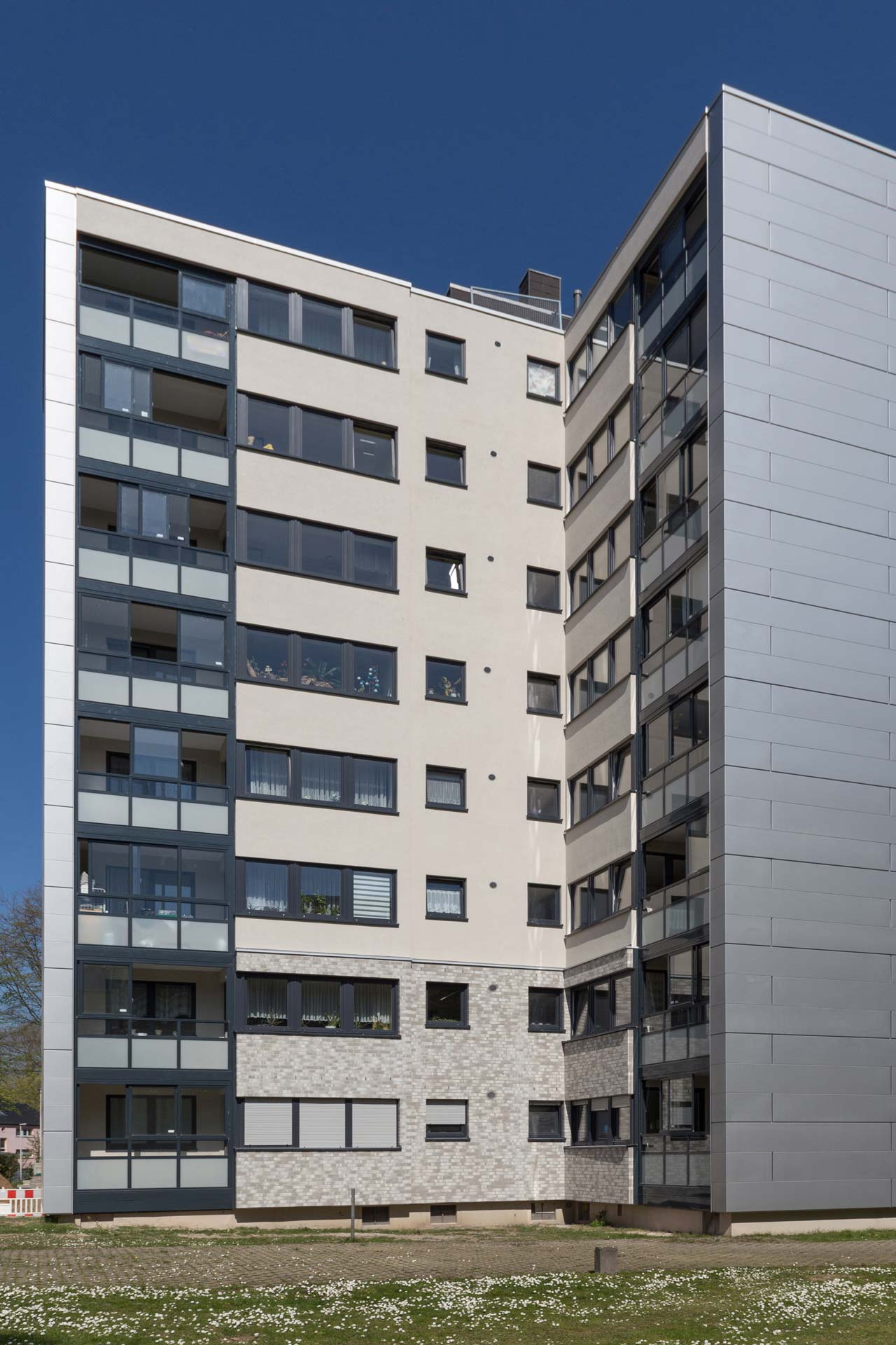 Mehrfamilienhaus aus den 70ern mit modernisierter Fassade in Graut&ouml;nen.