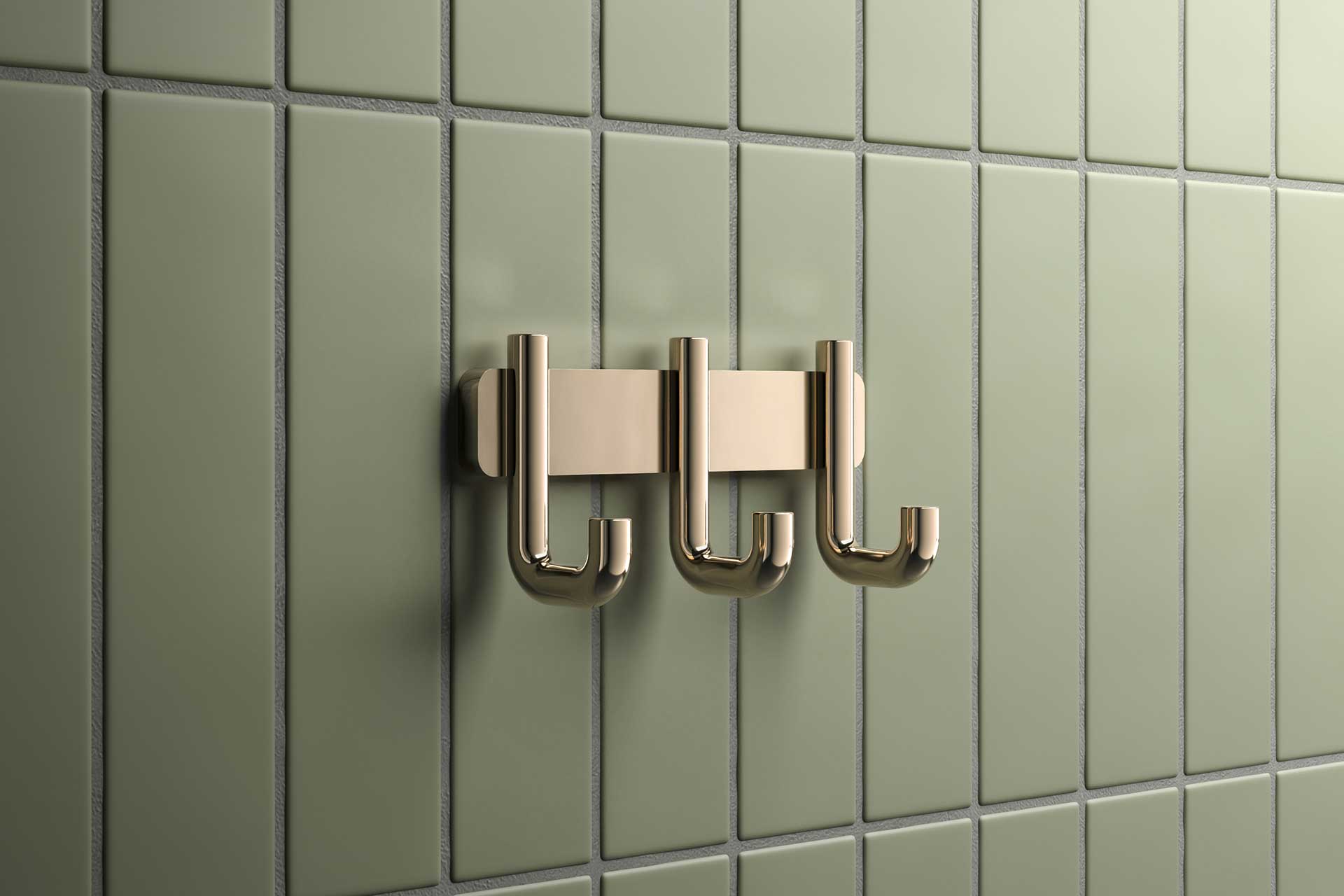 Vergoldeter Handtuchhaken sind an grünen Fliesen montiert.