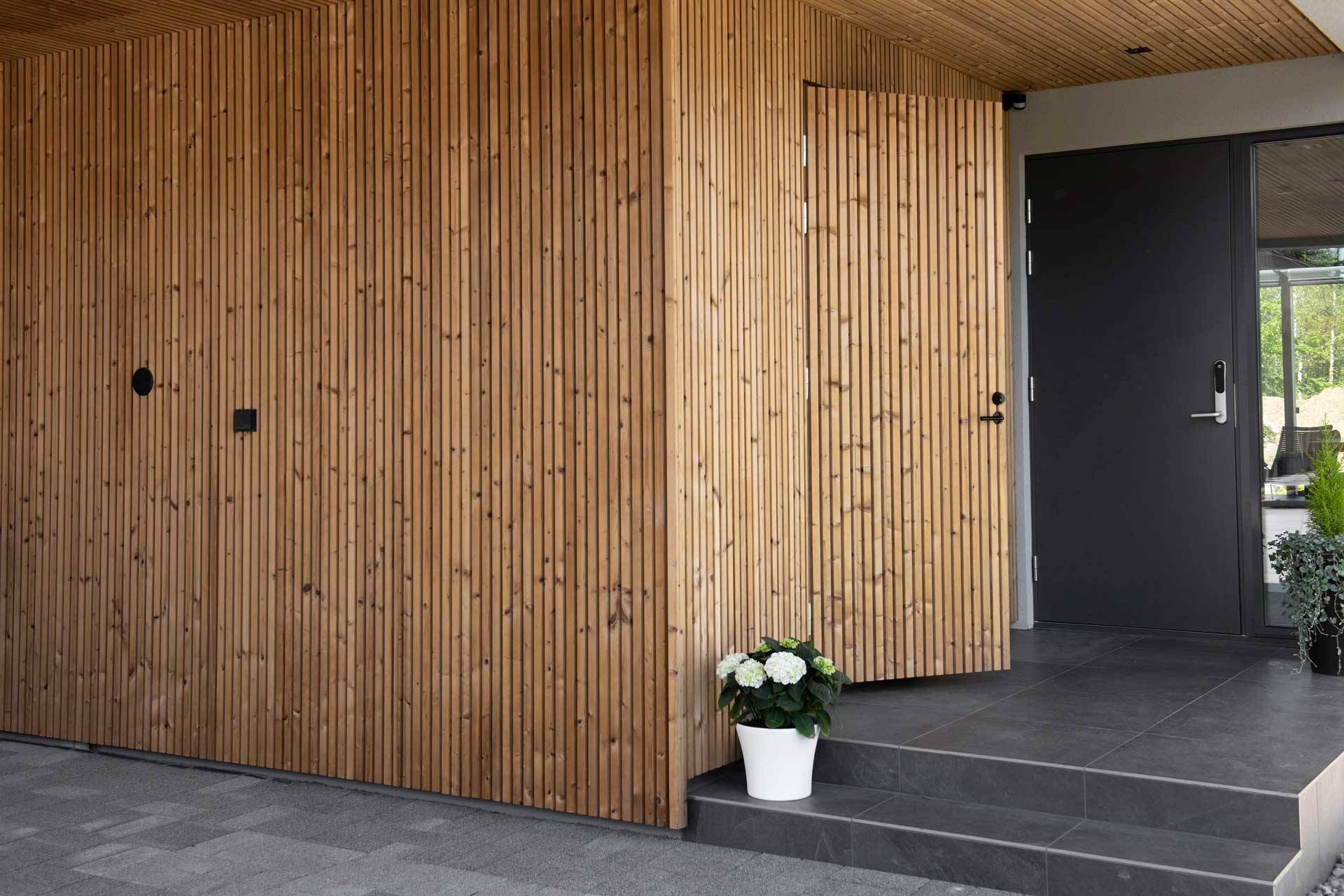 Eingangsbereich eines Hauses, der mit vertikalen, hellen Holzstreben verkleidet ist.