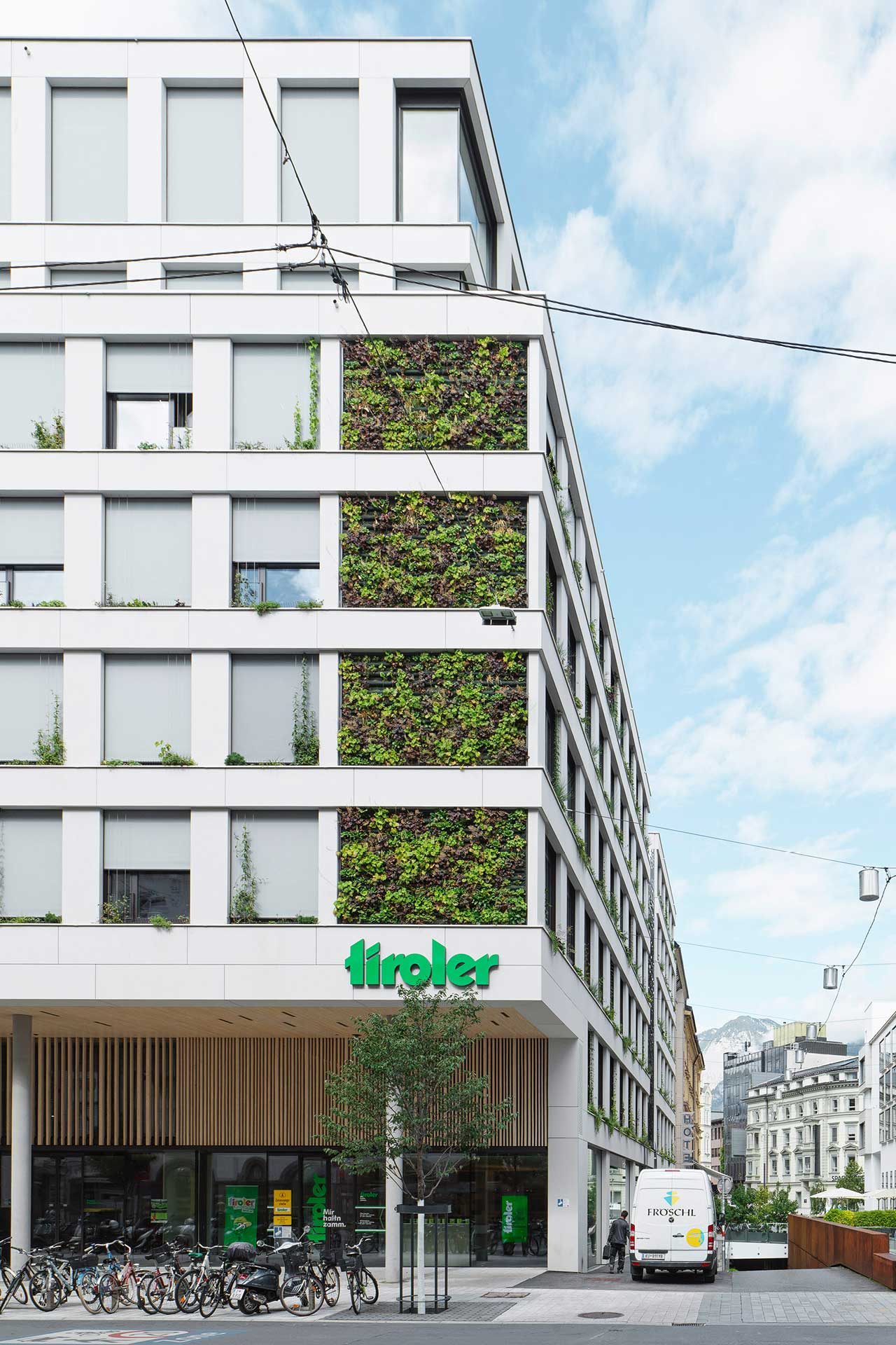 Eckansicht eines Bürogebäudes mit einer begünten Hauswand an einer Straße. 