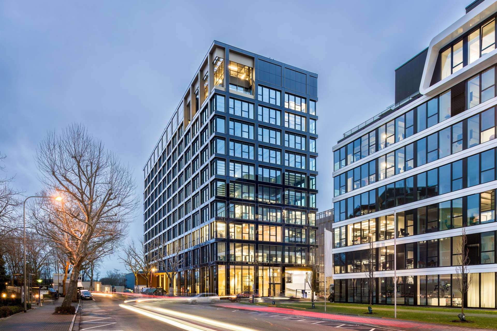 Beleuchtetes Bürogebäude bei Nacht an einer leeren Straße.