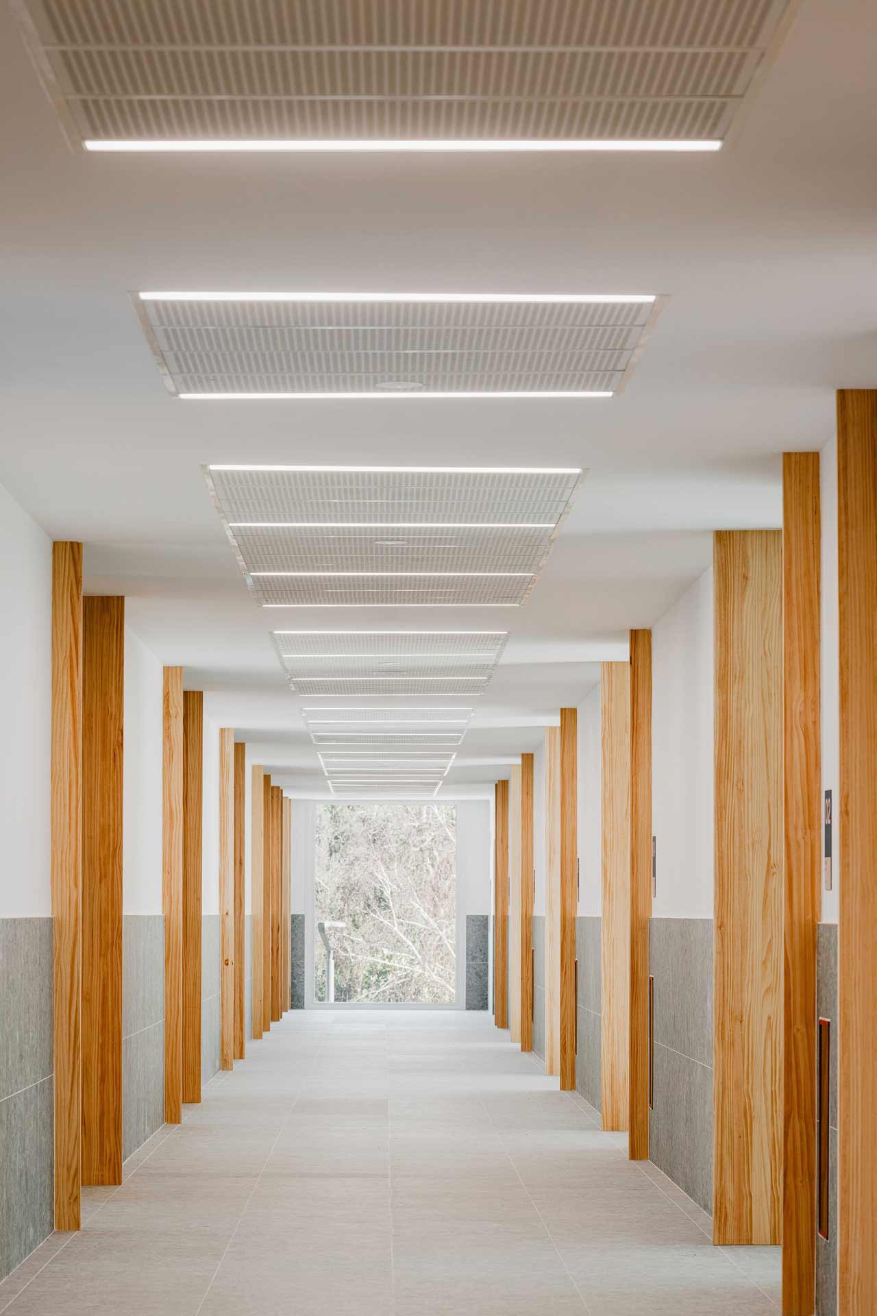 Heller Gang mit Holztüren und einem hellen Steinboden. 